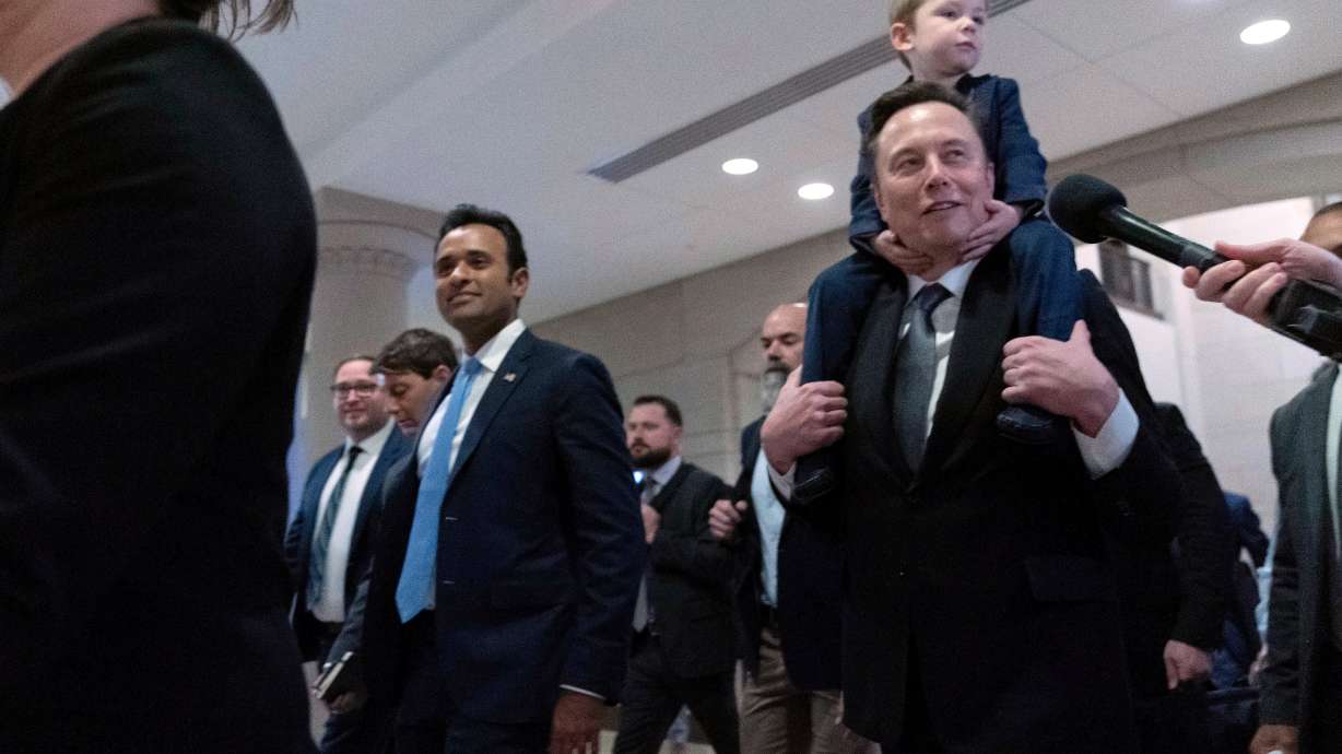 President-elect Donald Trump's pick for the planned Department of Government Efficiency Vivek Ramaswamy, center left, and Elon Musk, carrying his son X Æ A-Xii, arrive for a roundtable meeting at the Capitol, Thursday in Washington.
