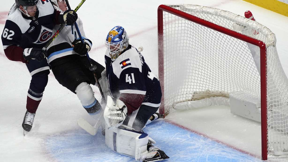 Colorado Avalanche left wing Artturi Lehkonen, left, blocks Utah Hockey Club right wing Dylan Guenther as his shot flies past Colorado goaltender Scott Wedgewood for a goal in the first period of an NHL hockey game Thursday, Dec. 12, 2024, in Denver.