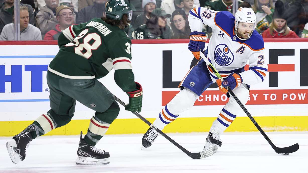 Edmonton Oilers center Leon Draisaitl, right, skates with the puck as Minnesota Wild right wing Ryan Hartman (38) defends during the second period of an NHL hockey game Thursday, Dec. 12, 2024, in St. Paul, Minn.