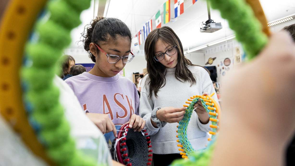 Sixth-graders Mayana Castillo, right, and Camille Vitela, use looms to make hats as part of a service project at Eagle Bay Elementary in Farmington on Wednesday.
