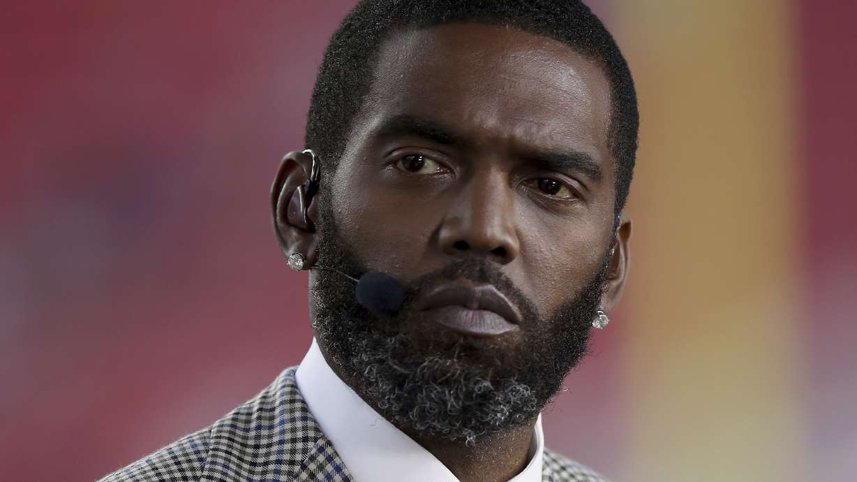 FILE - Broadcaster Randy Moss sits on the sideline before an NFL football game between the San Francisco 49ers and the Los Angeles Rams, Monday, Nov. 15, 2021, in Santa Clara, Calif.