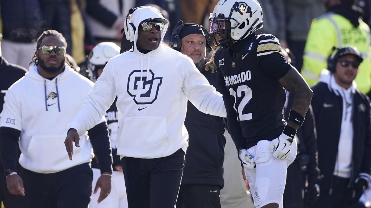 Colorado head coach Deion Sanders, left, confers with wide receiver Travis Hunter in the first half of an NCAA college football game against Oklahoma State Friday, Nov. 29, 2024, in Boulder, Colo.