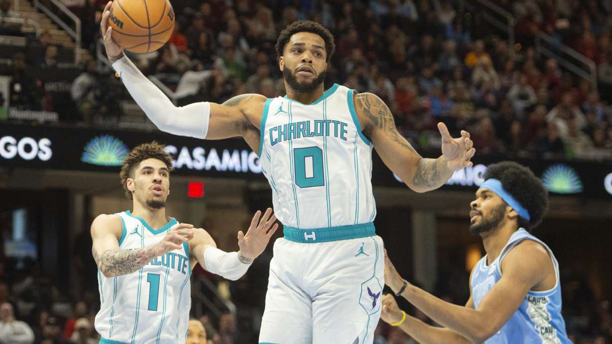 Charlotte Hornets' Miles Bridges (0) grabs a rebound in front of Cleveland Cavaliers' Jarrett Allen, right, and LaMelo Ball (1) during the first half of an NBA basketball game in Cleveland, Sunday, Nov 17, 2024.