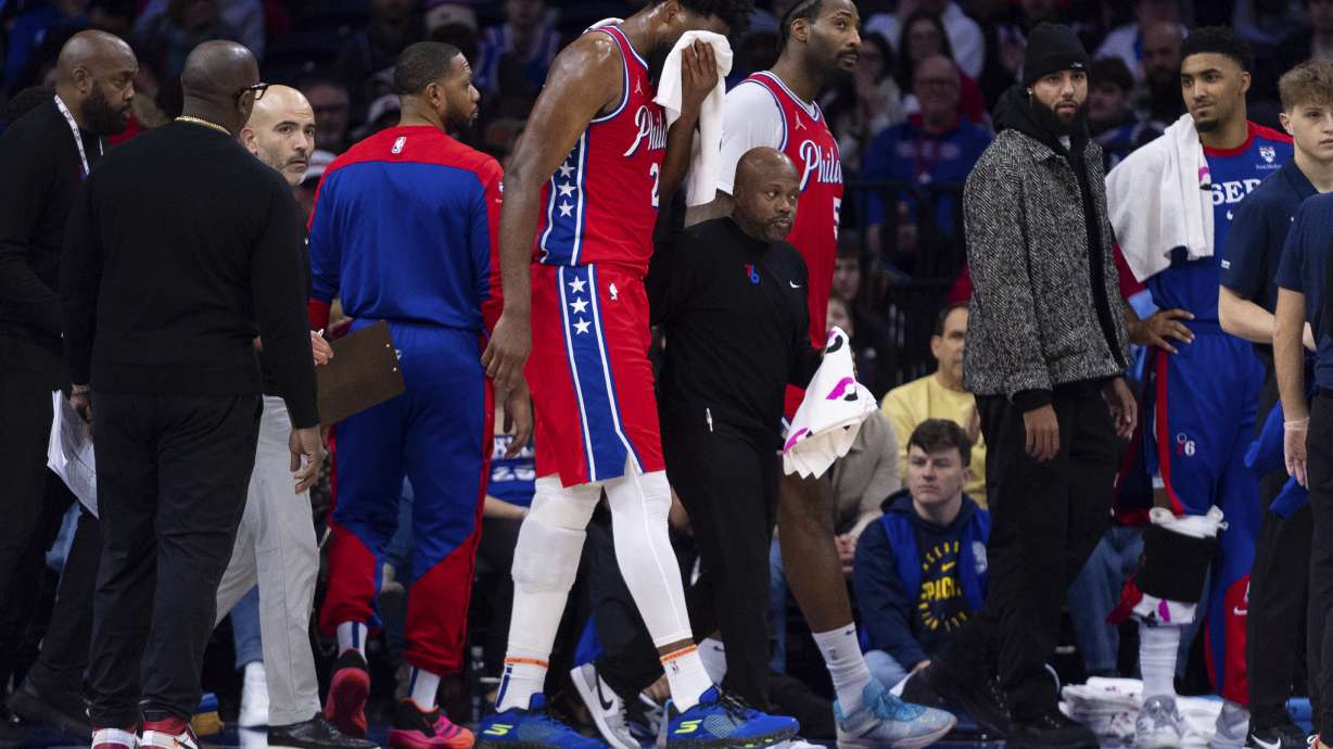 Philadelphia 76ers' Joel Embiid, center, gets helped off the court after getting hit in the face during the first half of an NBA basketball game against the Indiana Pacers, Friday, Dec. 13, 2024, in Philadelphia.