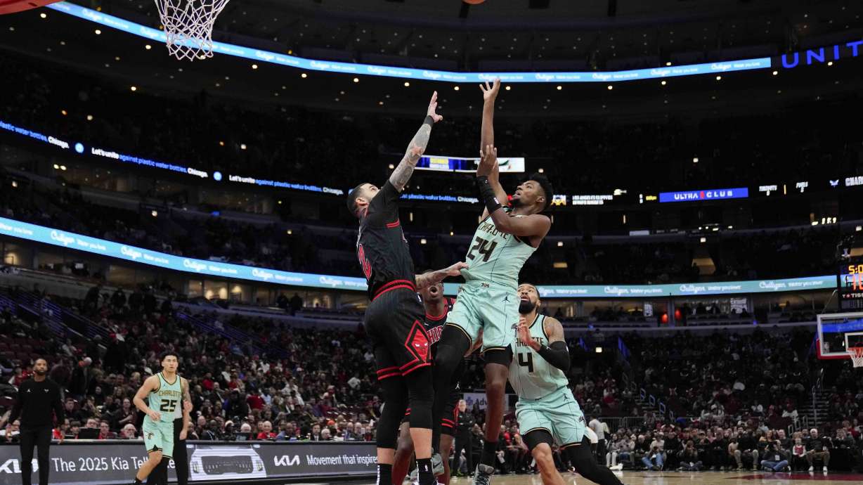 Chicago Bulls guard Lonzo Ball, center left, grabs the jersey of Charlotte Hornets forward Brandon Miller, center right, who attempts to shoot during the first half of an NBA basketball game Friday, Dec. 13, 2024, in Chicago.