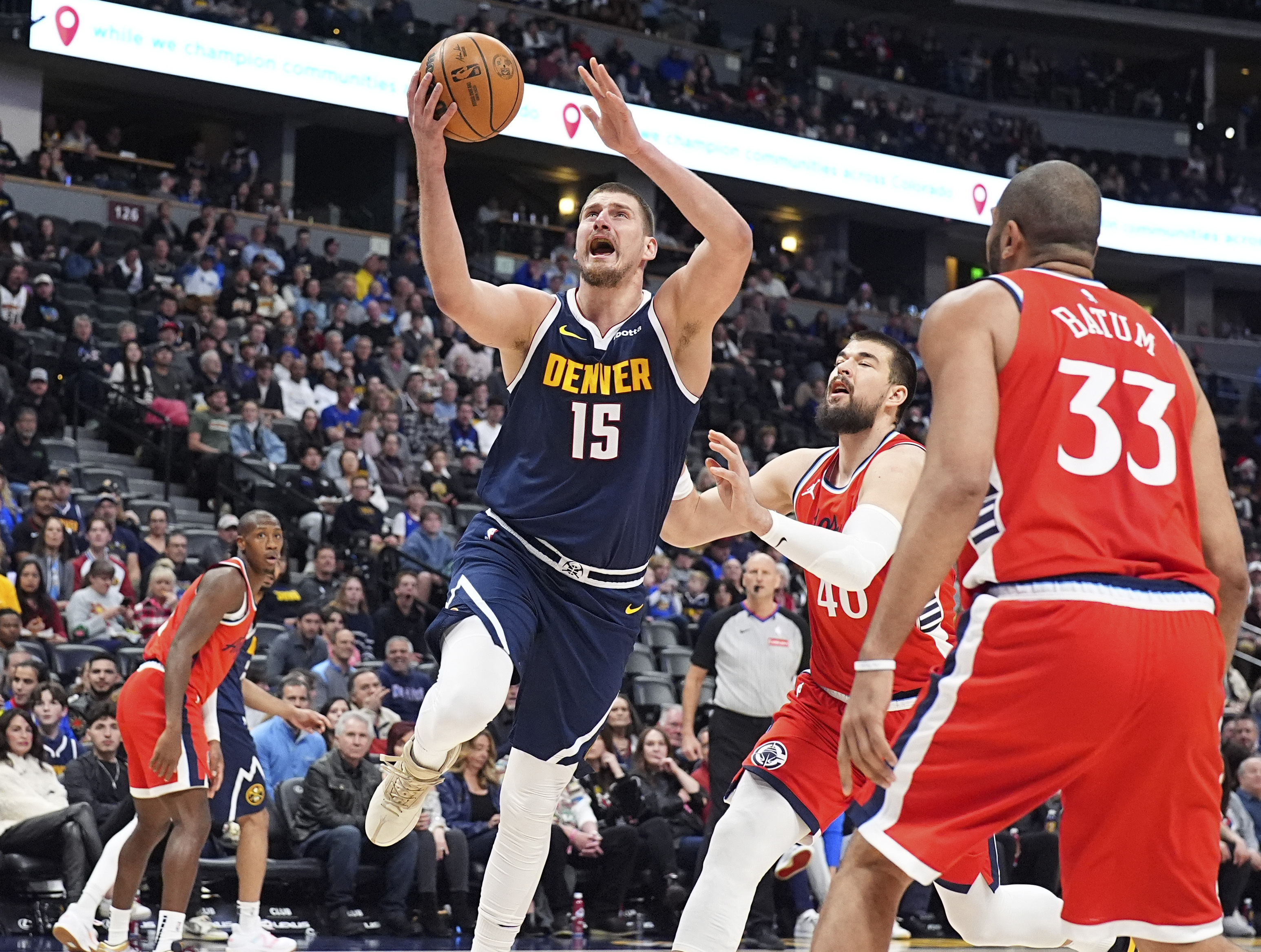 Denver Nuggets center Nikola Jokic (15) drives to the basket as Los Angeles Clippers center Ivica Zubac, back right, and forward Nicolas Batum (33) defend in the first half of an NBA basketball game Friday, Dec. 13, 2024, in Denver.