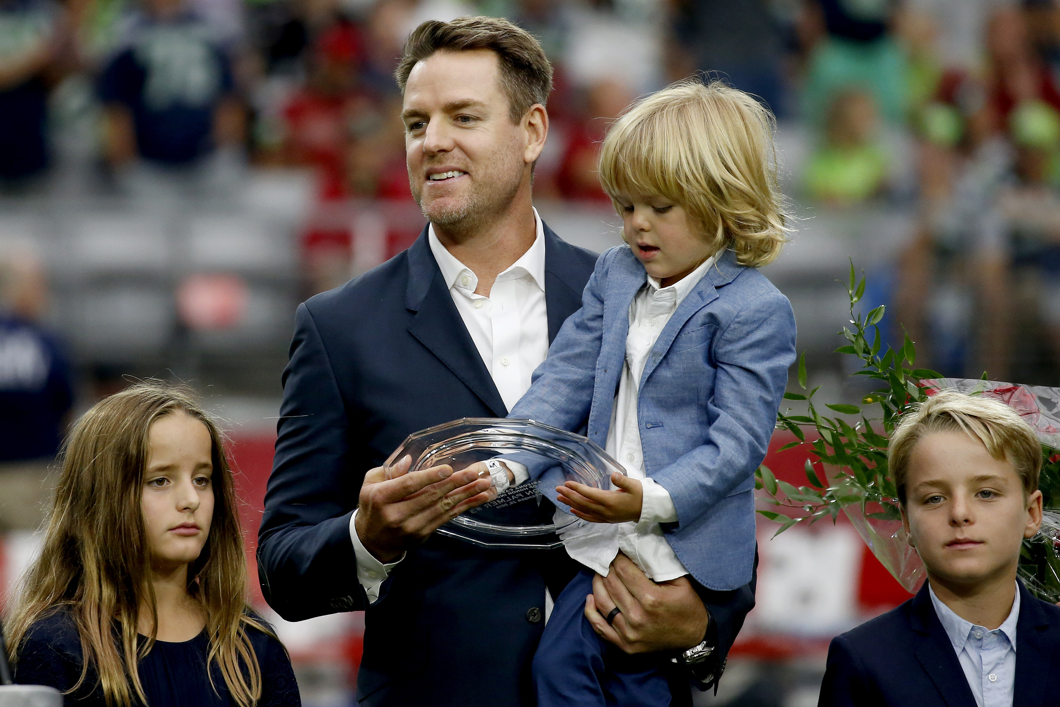 FILE - Former Arizona Cardinals quarterback Carson Palmer stands with his family after being added to the Cardinals ring of honor during a halftime game in Glendale, Ariz., Sept. 29, 2019.