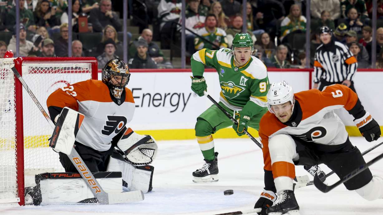 Philadelphia Flyers goaltender Samuel Ersson (33) prepares to save the puck while Flyers defenseman Travis Sanheim (6) dives to block and Minnesota Wild left wing Kirill Kaprizov (97) looks on during the first period of an NHL hockey game, Saturday, Dec. 14, 2024, in St. Paul, Minn.