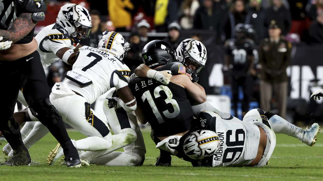 Navy defensive tackle Landon Robinson (96) takes down Army quarterback Bryson Daily (13) during the second half of an NCAA college football game, Saturday, Dec. 14, 2024, in Landover, Md.