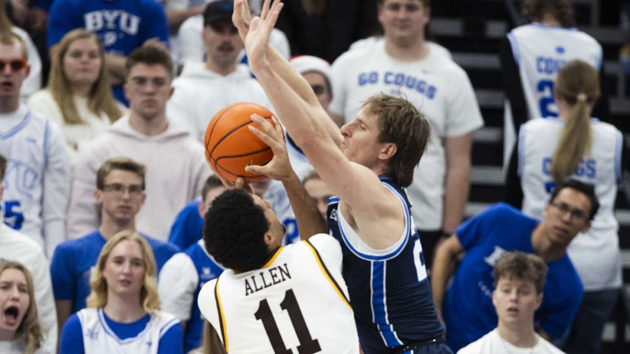 Brigham Young guard Dawson Baker (25) attempts to block a shot by Wyoming Cowboys guard Dontaie Allen (11) during a game between the Brigham Young Cougars and the Wyoming Cowboys at the Delta Center in Salt Lake City on Saturday, Dec. 14, 2024.