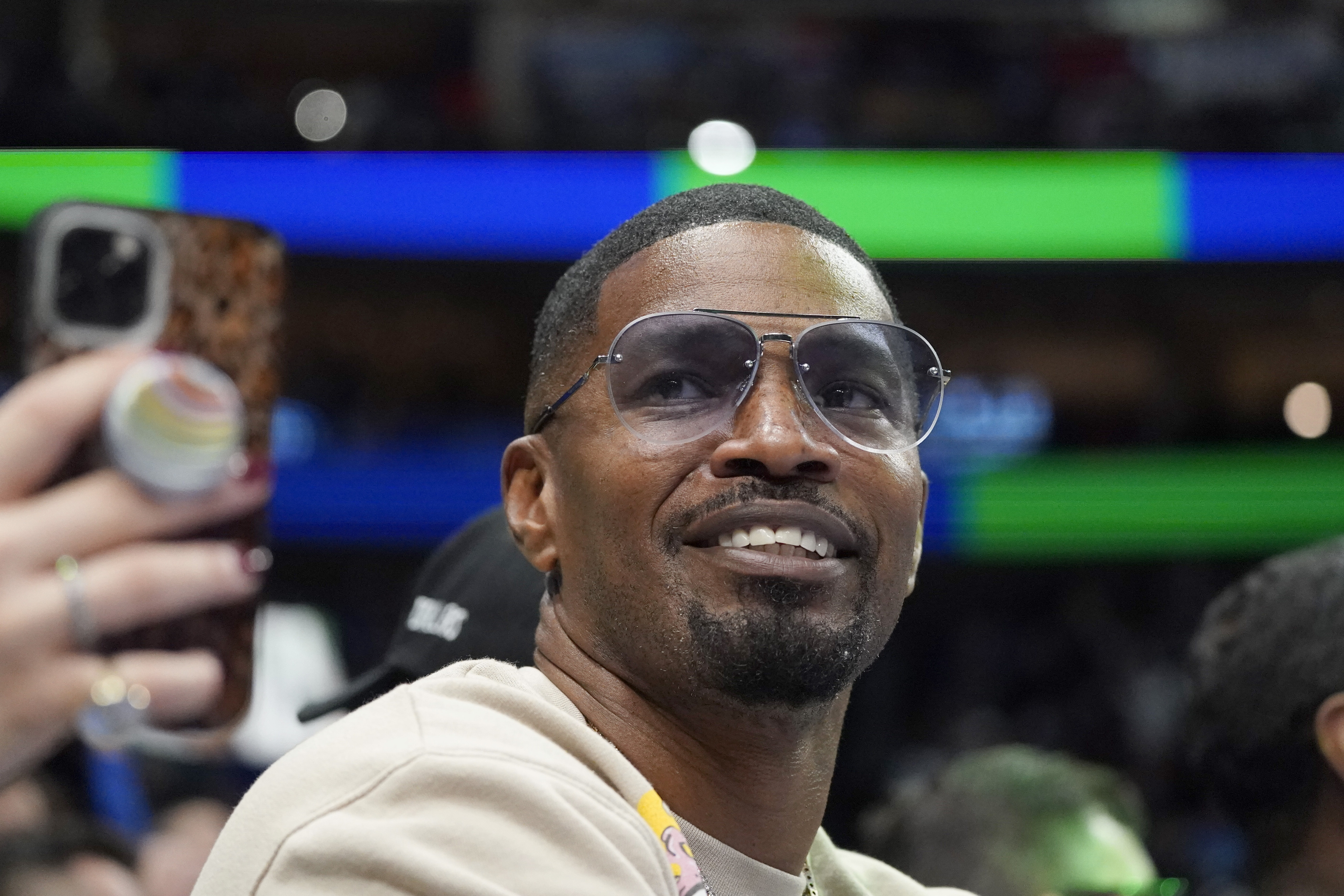Jamie Foxx smiles during an NBA basketball game in Dallas, Nov. 27, 2021. The actor required stitches after getting hit in the face with a glass while celebrating his birthday at a restaurant in Beverly Hills, California.