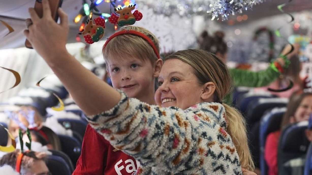 Kaelee Thomas, right, takes a selfie with her 7-year-old son, Greyson, before take off during the United Airlines annual "fantasy flight" to a North Pole at Denver International Airport, Saturday in Denver.