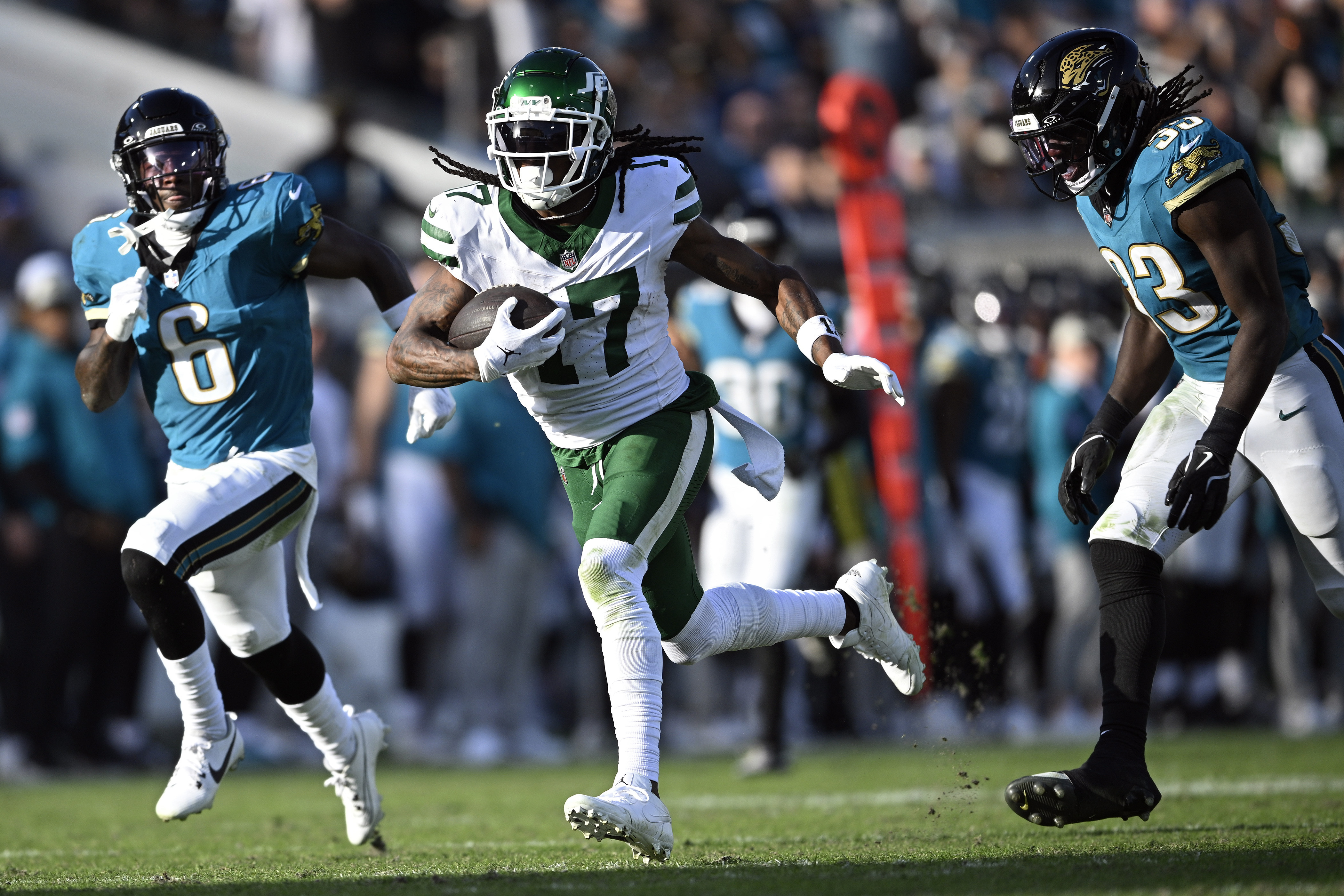 New York Jets wide receiver Davante Adams (17) gets between Jacksonville Jaguars safety Darnell Savage (6) and linebacker Devin Lloyd (33) tomscore on a 71-yard touchdown reception during the second half of an NFL football game Sunday, Dec. 15, 2024, in Jacksonville, Fla.