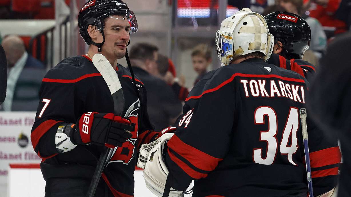 Carolina Hurricanes goaltender Dustin Tokarski (34) is congratulated on his win over the Columbus Blue Jackets by teammate Dmitry Orlov (7) following an NHL hockey game in Raleigh, N.C., Sunday, Dec. 15, 2024.