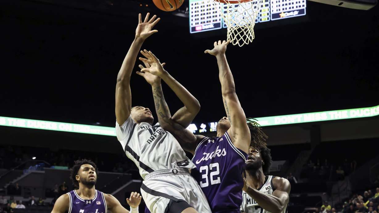 Oregon forward Kwame Evans Jr., center left, shoots against Stephen F. Austin forward Juhlawnei Stone (32) during the first half of an NCAA college basketball game in Eugene, Ore., Sunday, Dec. 15, 2024.
