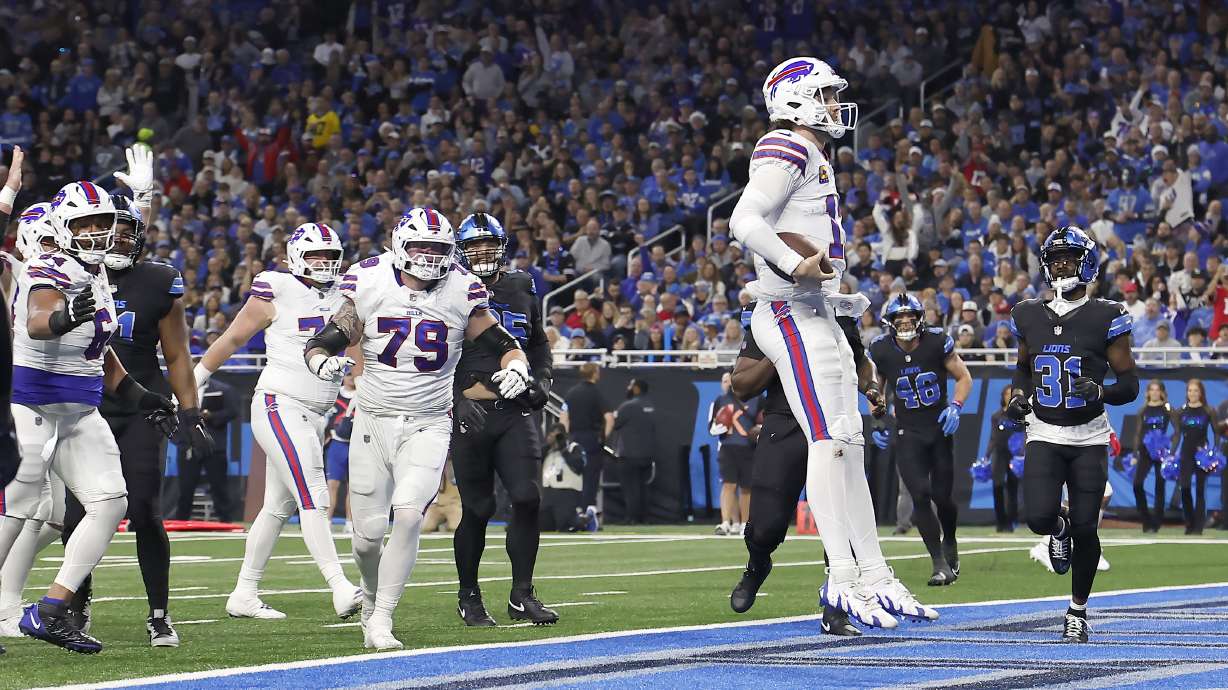 Buffalo Bills quarterback Josh Allen, foreground, celebrates after scoring against the Detroit Lions during the first half of an NFL football game, Sunday, Dec. 15, 2024, in Detroit.