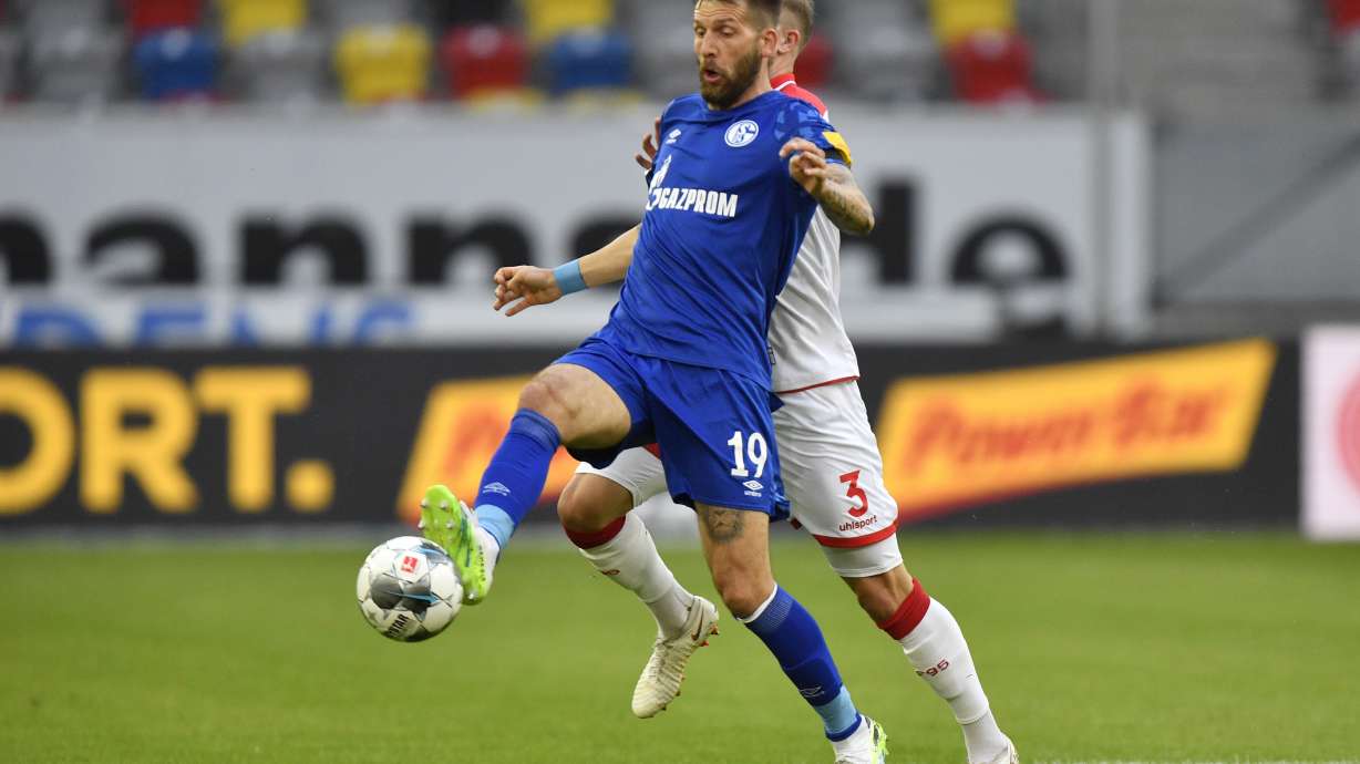 FILE - Schalke's Guido Burgstaller, left, is challenged by Duesseldorf's Andre Hoffman during the German Bundesliga soccer match between Fortuna Duesseldorf and FC Schalke 04 in Duesseldorf, Germany, on May 27, 2020.