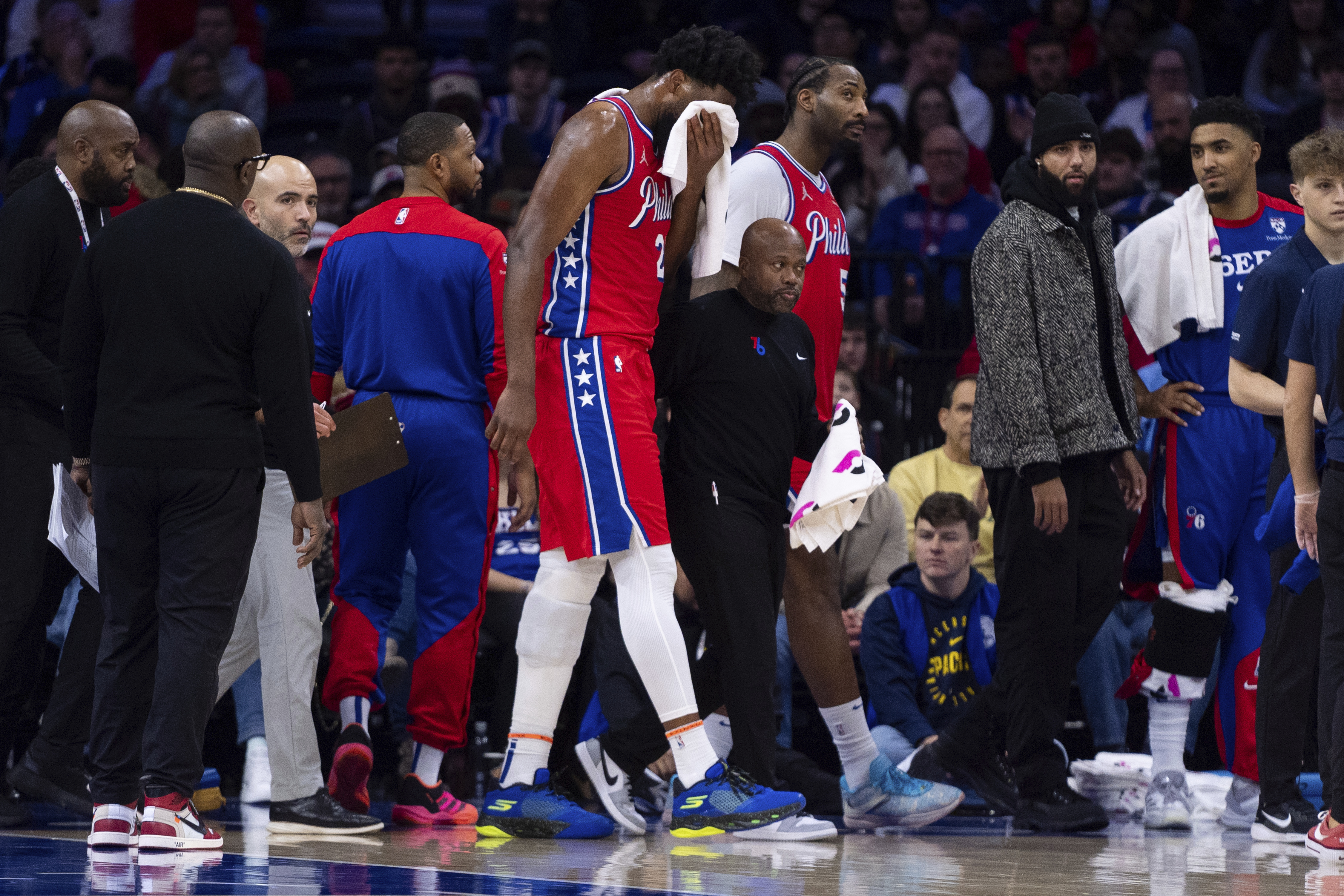 Philadelphia 76ers' Joel Embiid, center, gets helped off the court after getting hit in the face during the first half of an NBA basketball game against the Indiana Pacers, Friday, Dec. 13, 2024, in Philadelphia. 