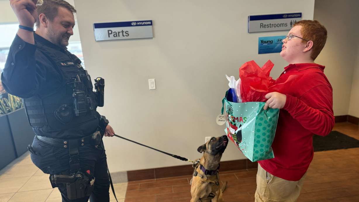 Officer Britton Griggs, left, tries to distract his K-9 dog, Anya. Anya, a recent member of the North Ogden Police Department, was more interested in getting her presents from the Christmas party for K-9 dogs held on Monday in Ogden.