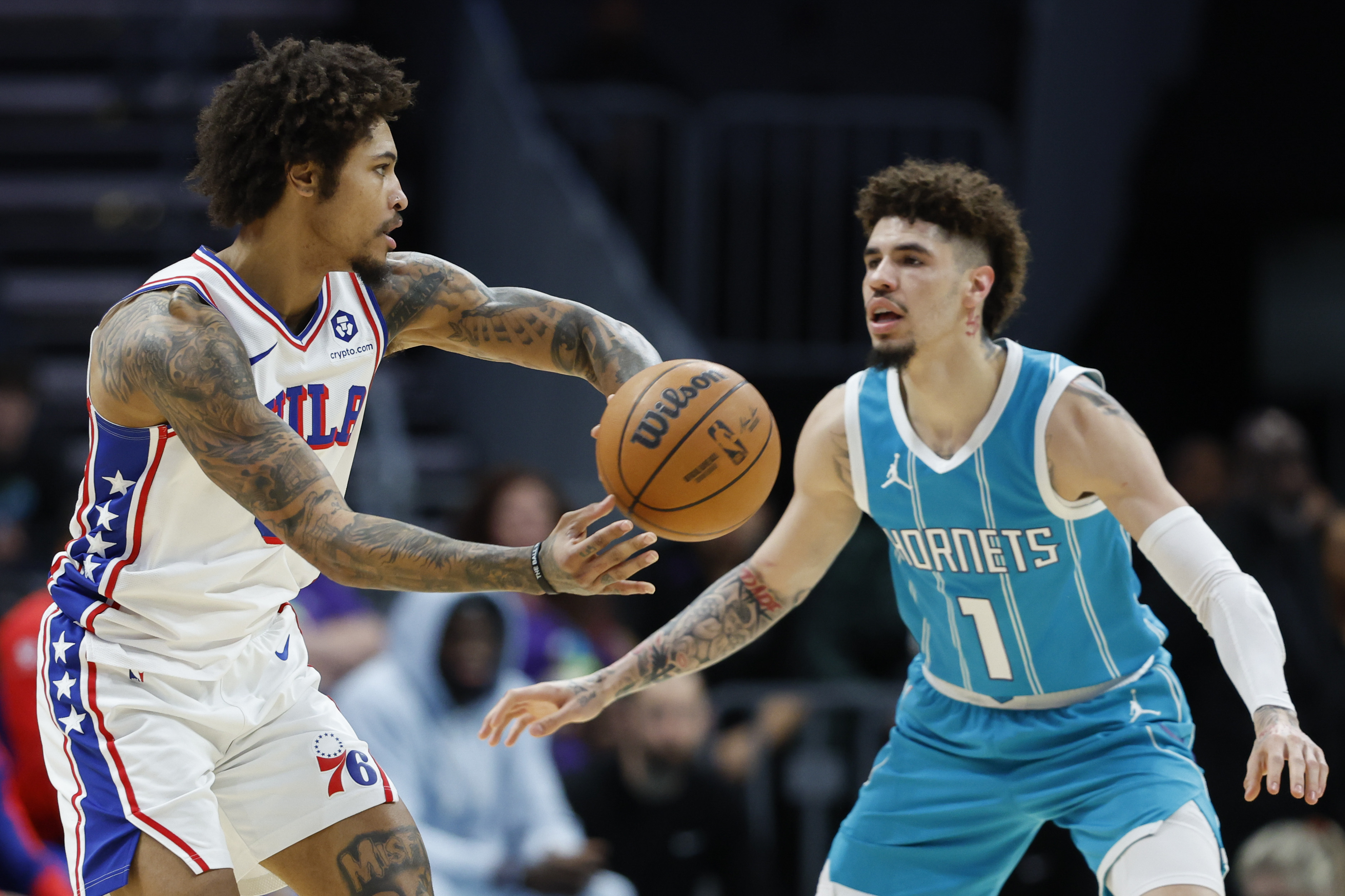 Philadelphia 76ers guard Kelly Oubre Jr., left, looks to pass the ball against Charlotte Hornets guard LaMelo Ball, right, during the first half of an NBA basketball game in Charlotte, N.C., Monday, Dec. 16, 2024. 