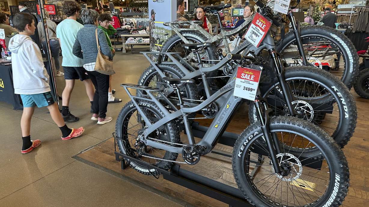 Shoppers pass by electric bicycles on display in a Cabela's sporting goods store Dec. 8, in Lone Tree, Colo. Consumers stepped up their spending at retail stores last month, providing a boost to the economy, the government reported Tuesday.