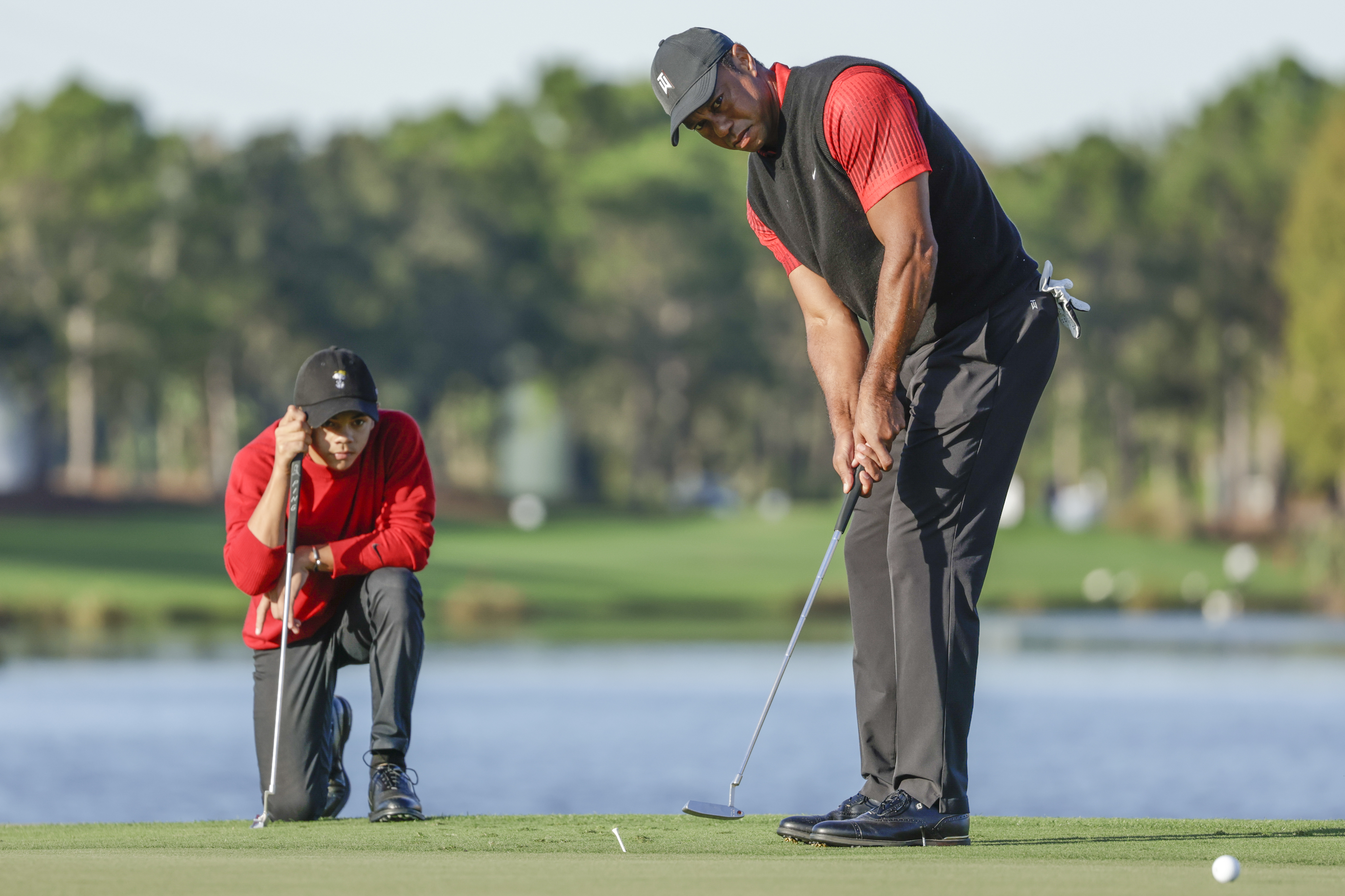 Charlie Woods, left, watches his father Tiger Woods, right, watches during the final round of the PNC Championship golf tournament, Dec. 18, 2022, in Orlando, Fla.