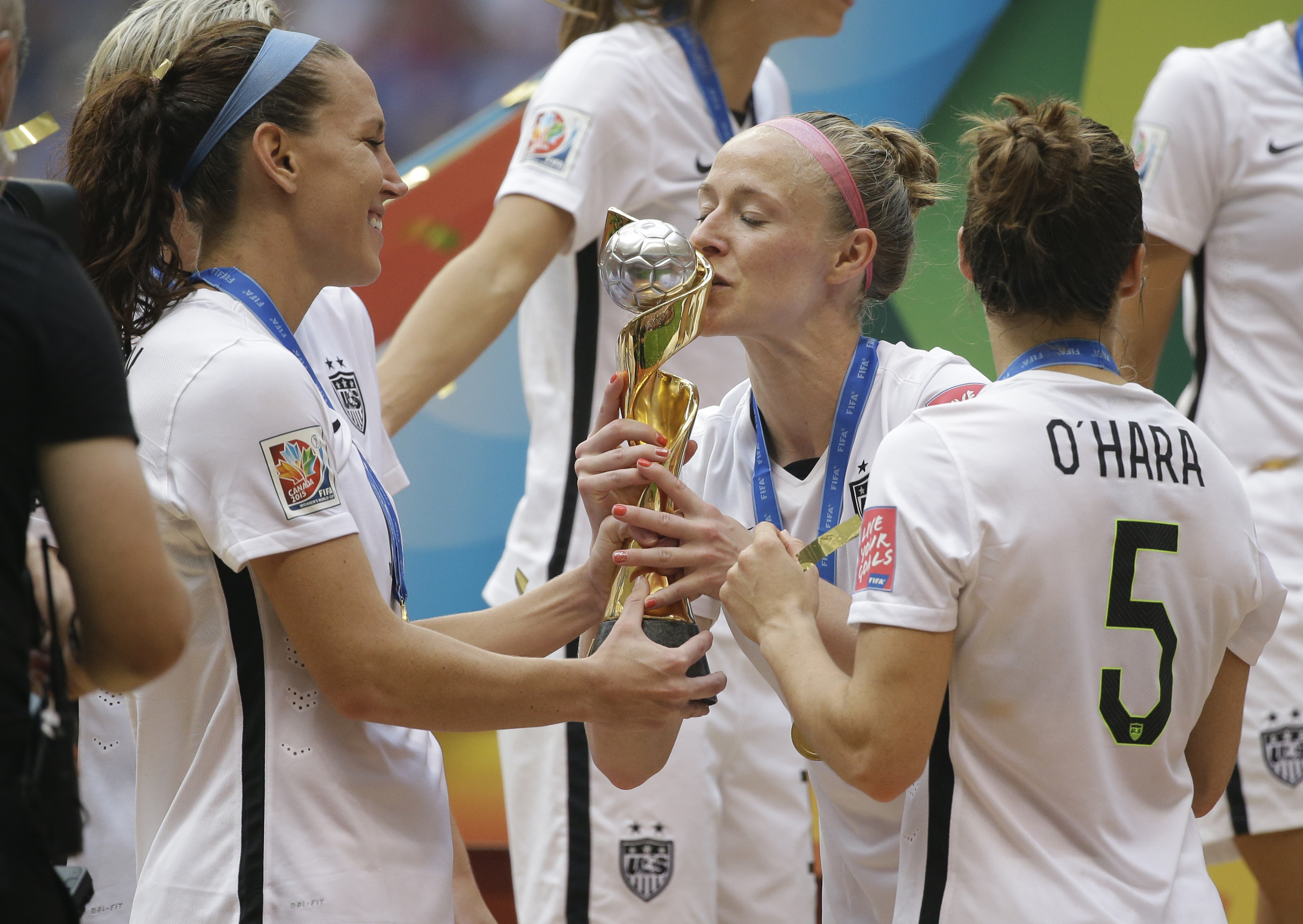 FILE _ United States' Becky Sauerbrunn, right, kisses the trophy as Lauren Holiday, left, and Kelley O'Hara, right, look on after the U.S. beat Japan 5-2 in the FIFA Women's World Cup soccer championship in Vancouver, British Columbia, Sunday, July 5, 2015.