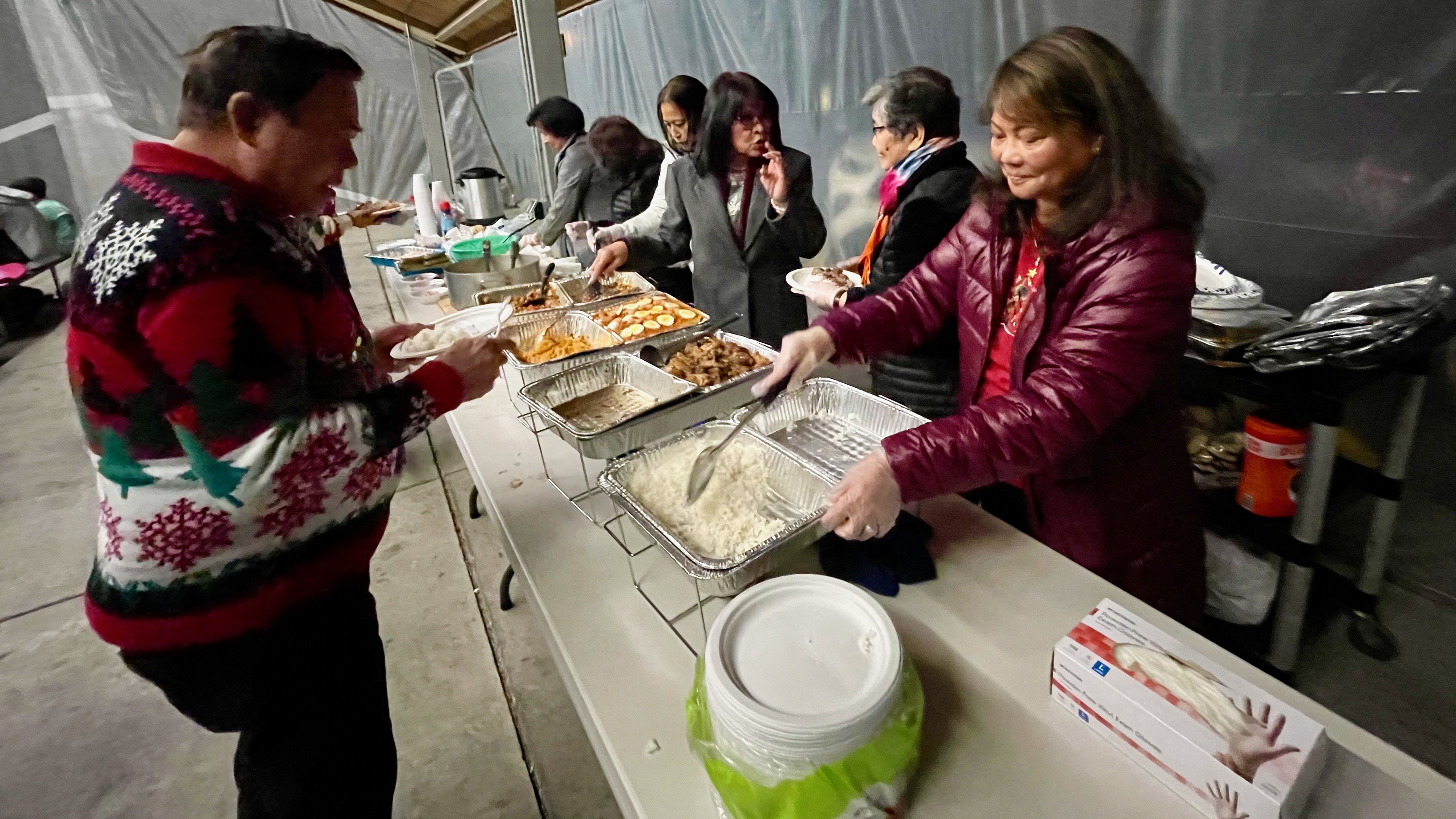 Marius Bondoc, left, at a shared meal after a Simbang Gabi service on Monday at Our Lady of Guadalupe Catholic Church in Salt Lake City. Simbang Gabi is a Christmastime tradition among Catholic Filipinos.