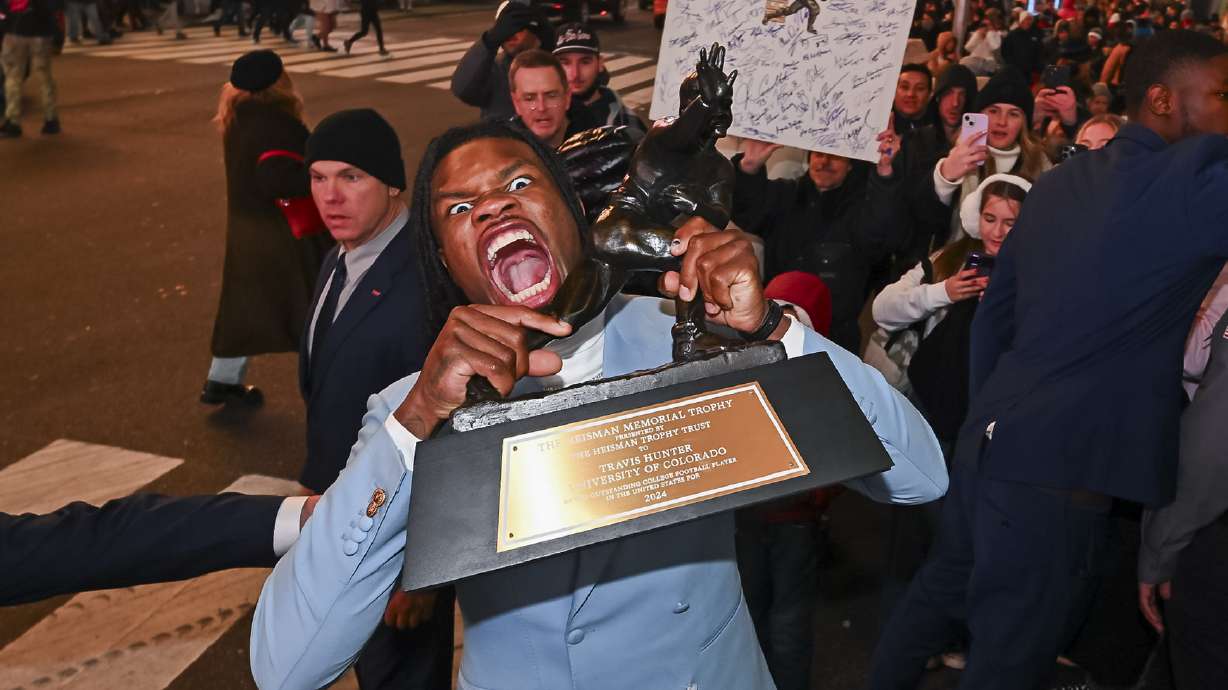 Travis Hunter poses in Times Square with the Heisman Trophy after winning it as the outstanding player in college football Saturday, Dec. 14, 2024, in New York.