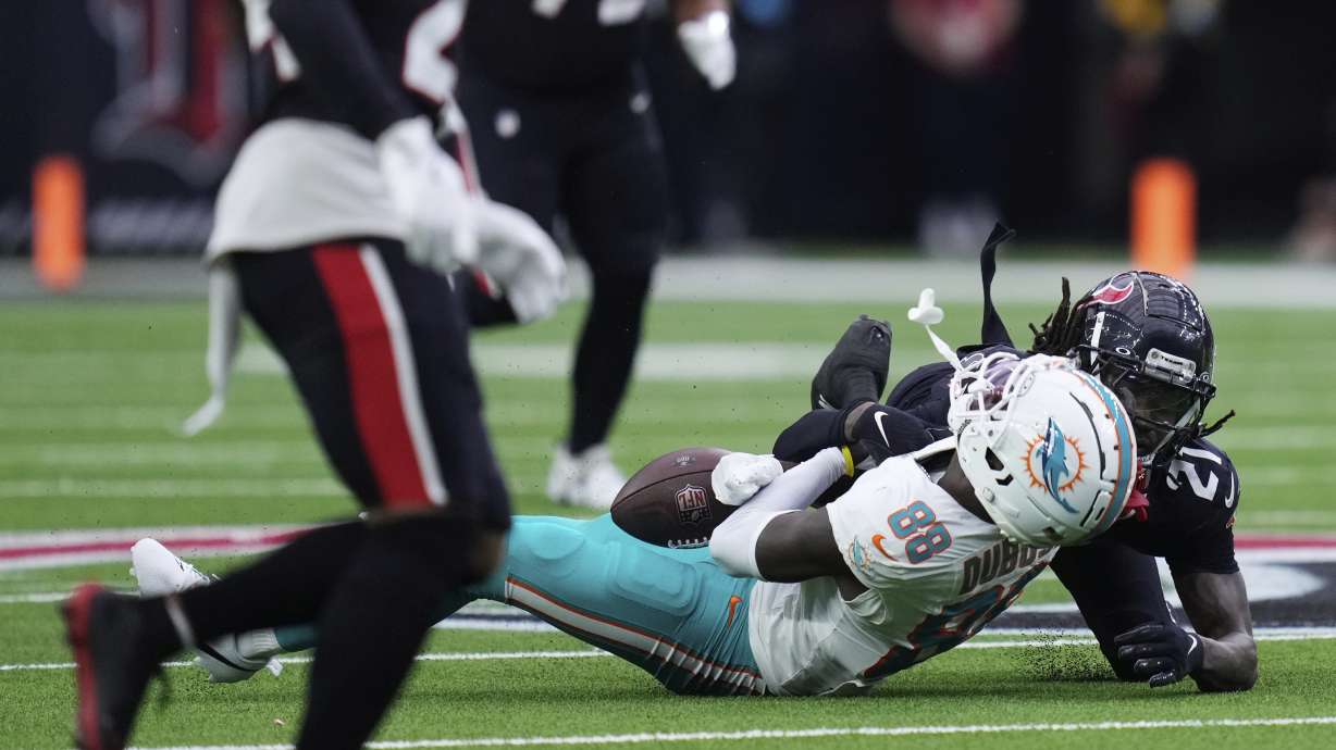 Miami Dolphins wide receiver Grant DuBose (88) is brought down by Houston Texans safety Calen Bullock (21) on a play that left DuBose injured, during the second half of an NFL football game Sunday, Dec. 15, 2024, in Houston.