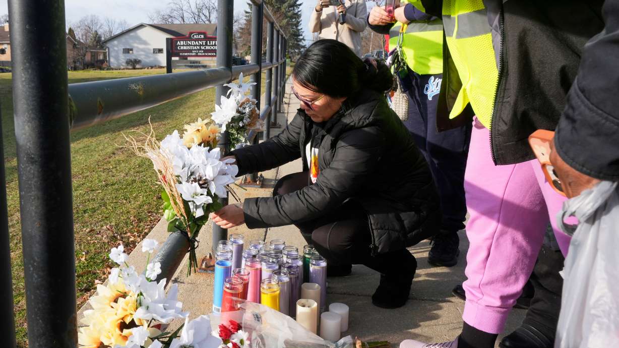 A resident places some flowers outside the Abundant Life Christian School, Tuesday in Madison, Wis., following a shooting on Monday.