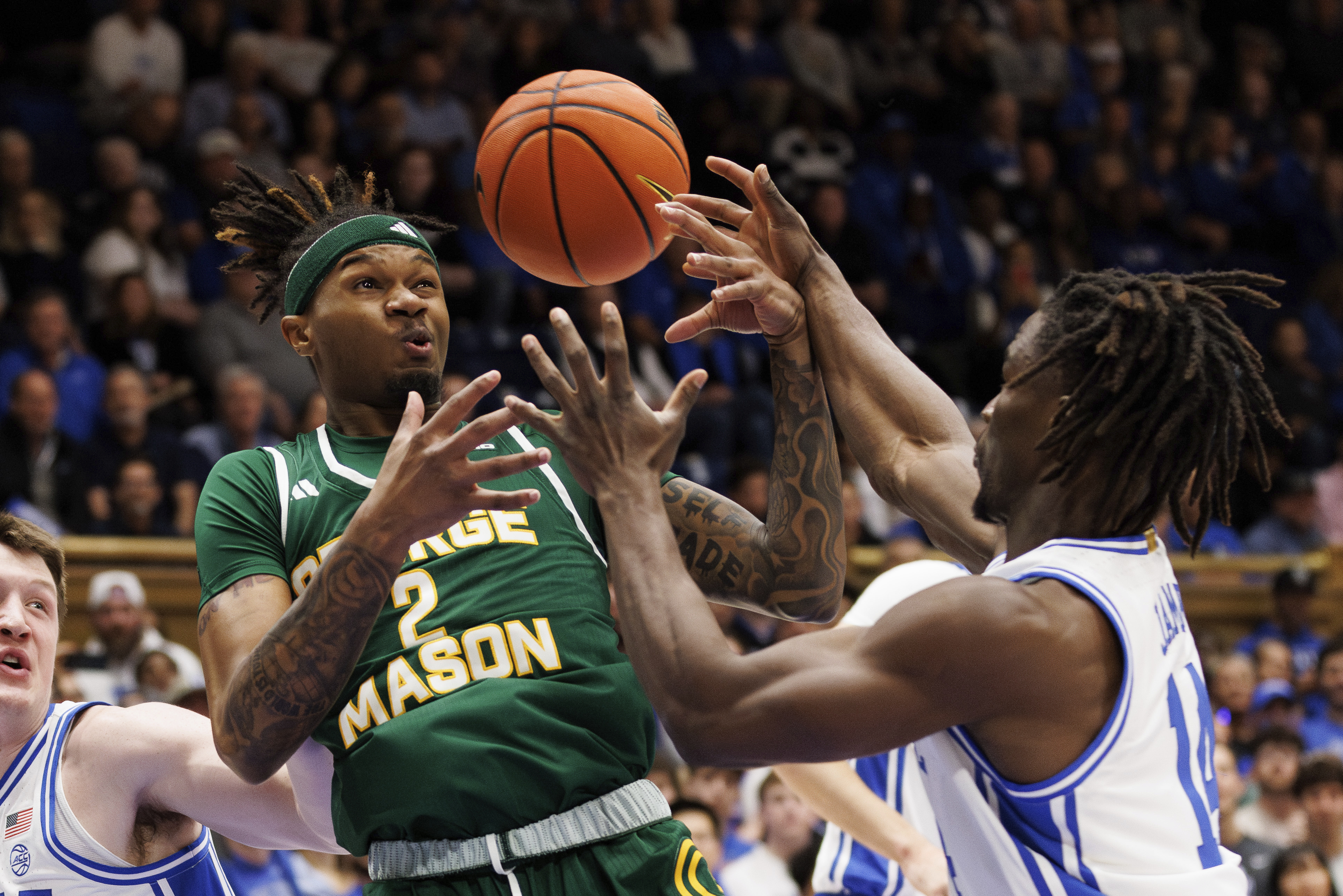 George Mason's Woody Newton (2) and Duke's Sion James (14) reach for a loose ball during the first half of an NCAA college basketball game in Durham, N.C., Tuesday, Dec. 17, 2024. 