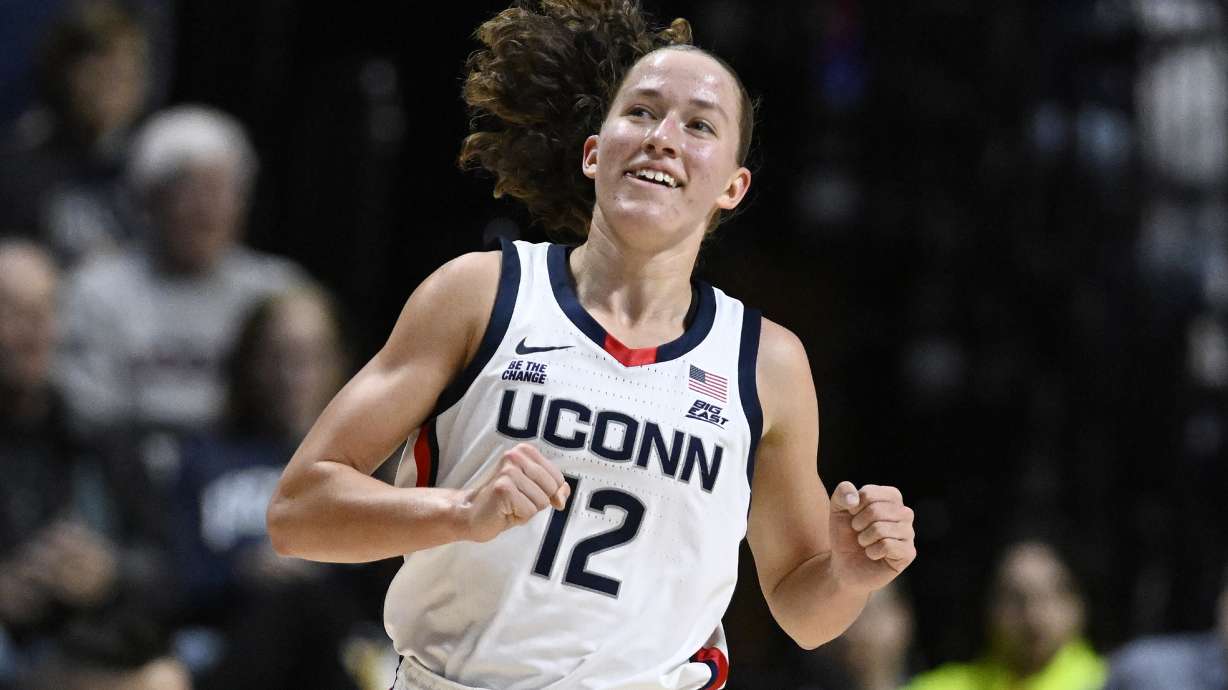 UConn guard Ashlynn Shade (12) smiles after making another three-point basket in the first half of an NCAA college basketball game against Iowa State, Tuesday, Dec. 17, 2024, in Uncasville, Conn.