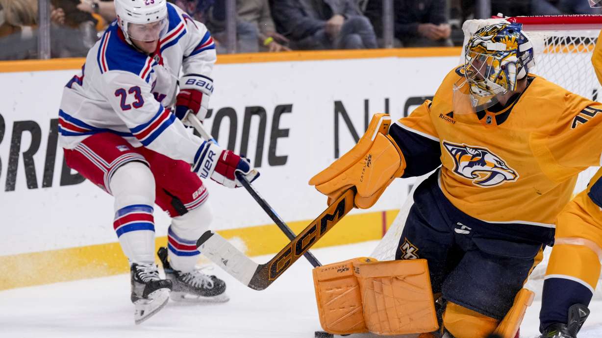 Nashville Predators goaltender Juuse Saros (74) blocks a shot on goal against the New York Rangers defenseman Adam Fox (23) during the first period of an NHL hockey game Tuesday, Dec. 17, 2024, in Nashville, Tenn.