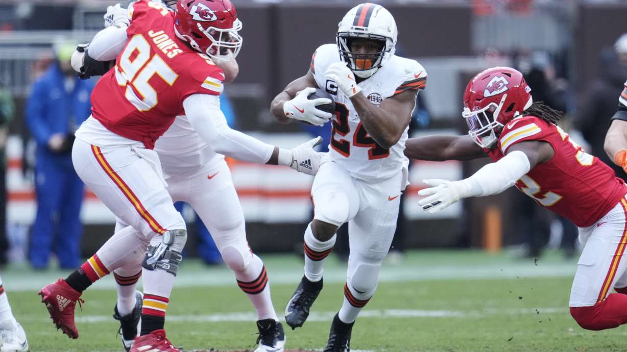 Cleveland Browns running back Nick Chubb, center, carries the ball between Kansas City Chiefs defensive tackle Chris Jones (95) and linebacker Nick Bolton, right, in the first half of an NFL football game in Cleveland, Sunday, Dec. 15, 2024.