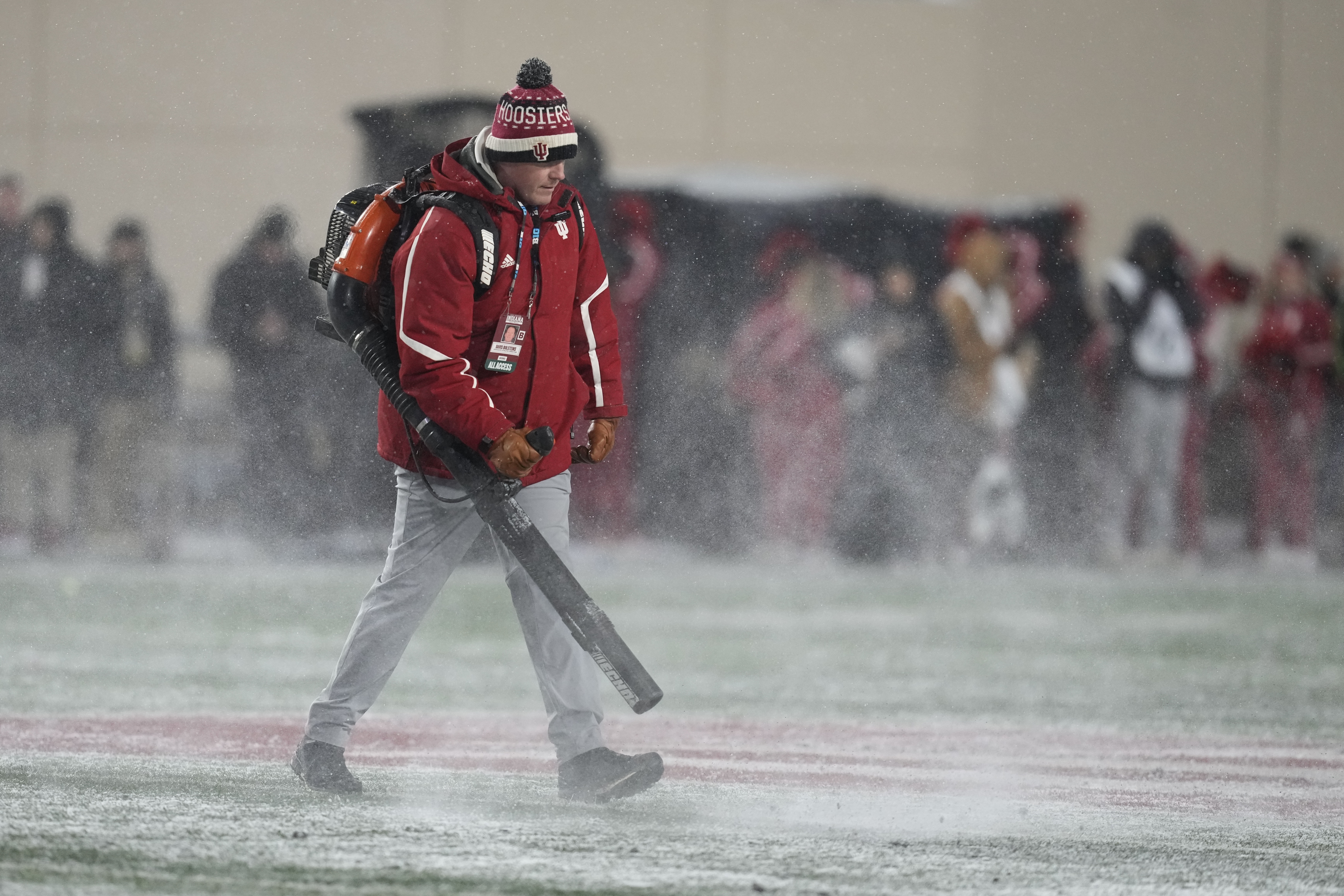 FILE - A worker cleans snow from the field during the first half of an NCAA college football game between Indiana and Purdue, Nov. 30, 2024, in Bloomington, Ind. 