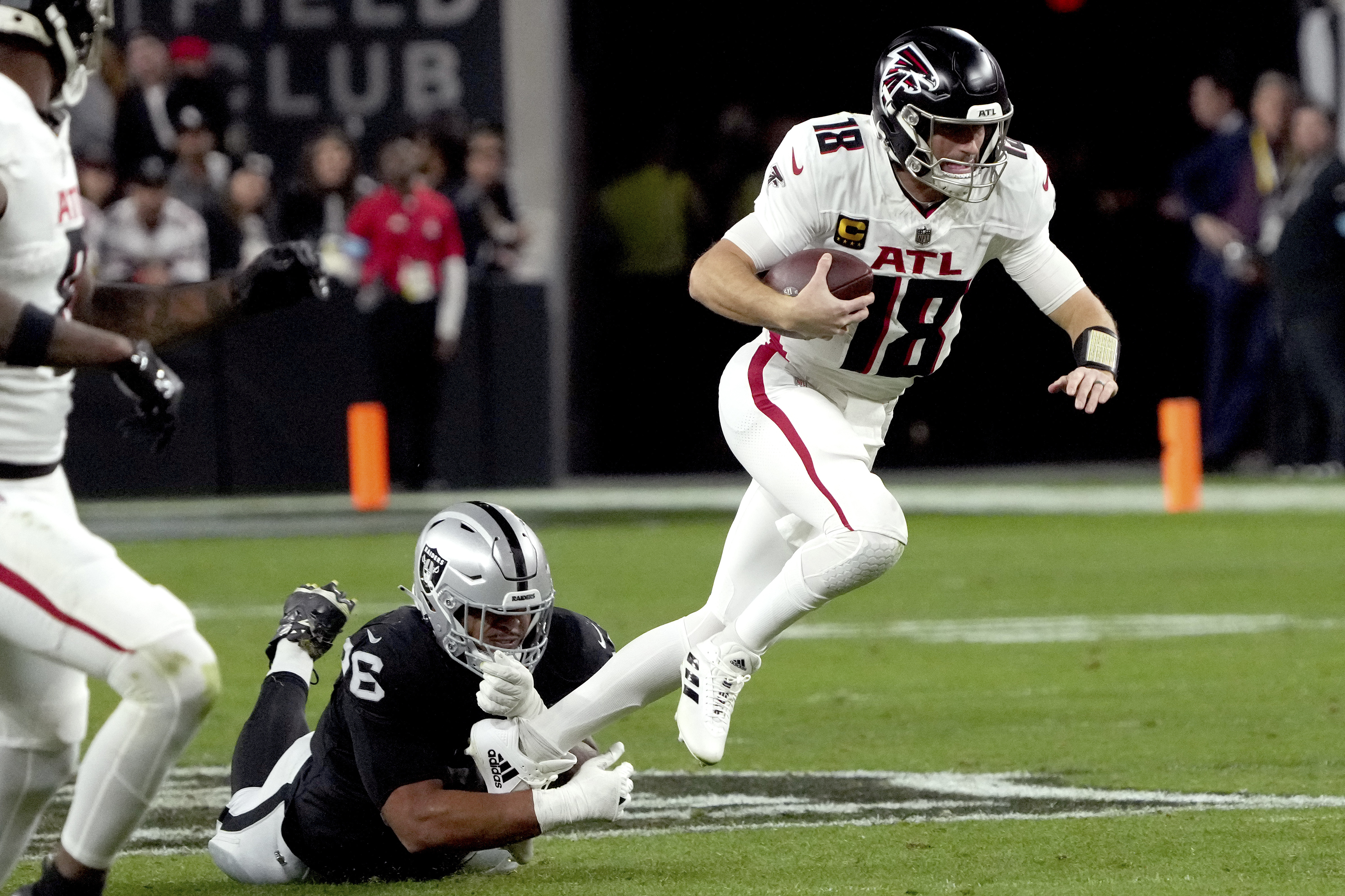 Atlanta Falcons quarterback Kirk Cousins (18) is tripped up by Las Vegas Raiders defensive tackle Jonah Laulu (96) during the first half of an NFL football game, Monday, Dec. 16, 2024, in Las Vegas. 