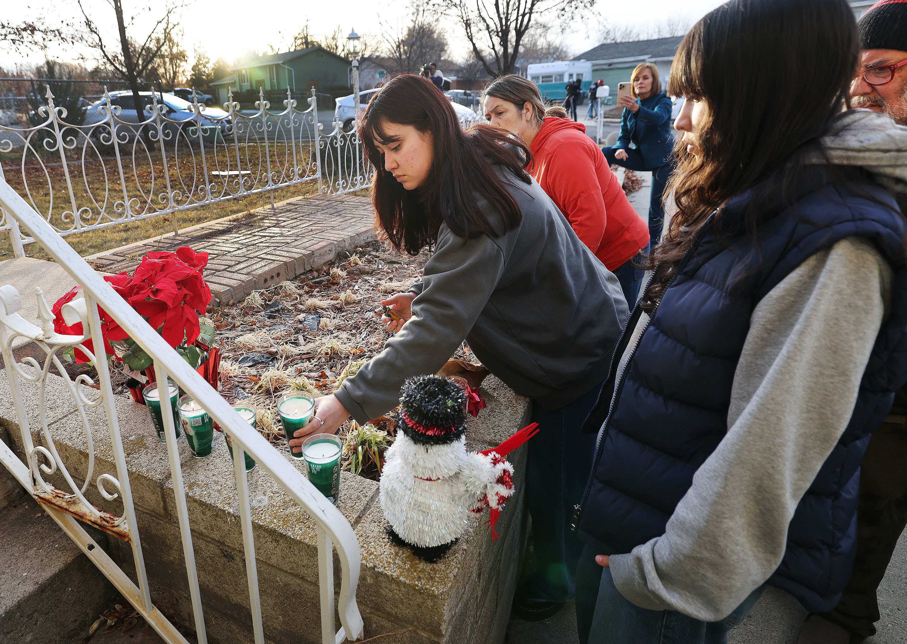 Anita and her sister Alanis along with their parents Astrid and Robinson Pinilla light candles on the steps Wednesday after five of their neighbors were found dead in their home in West Valley City on Tuesday. West Valley police say evidence indicates the father killed his family over the weekend.