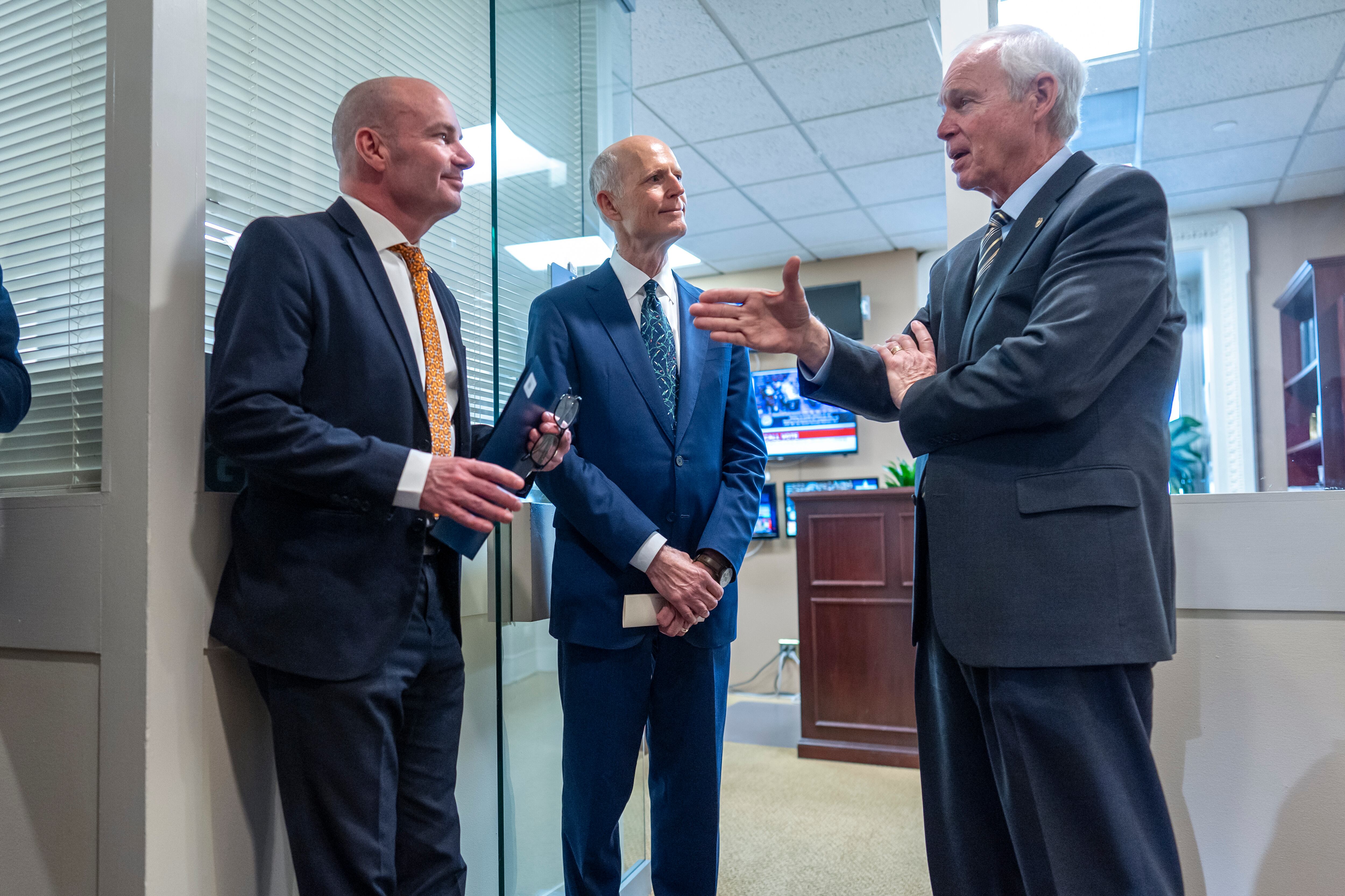 Sen. Mike Lee, R-Utah; Sen. Rick Scott, R-Fla.; and Sen. Ron Johnson, R-Wis., confer before joining other conservative Republicans to complain to reporters about the interim spending bill being crafted to avoid a shutdown of federal agencies, at the Capitol Wednesday.