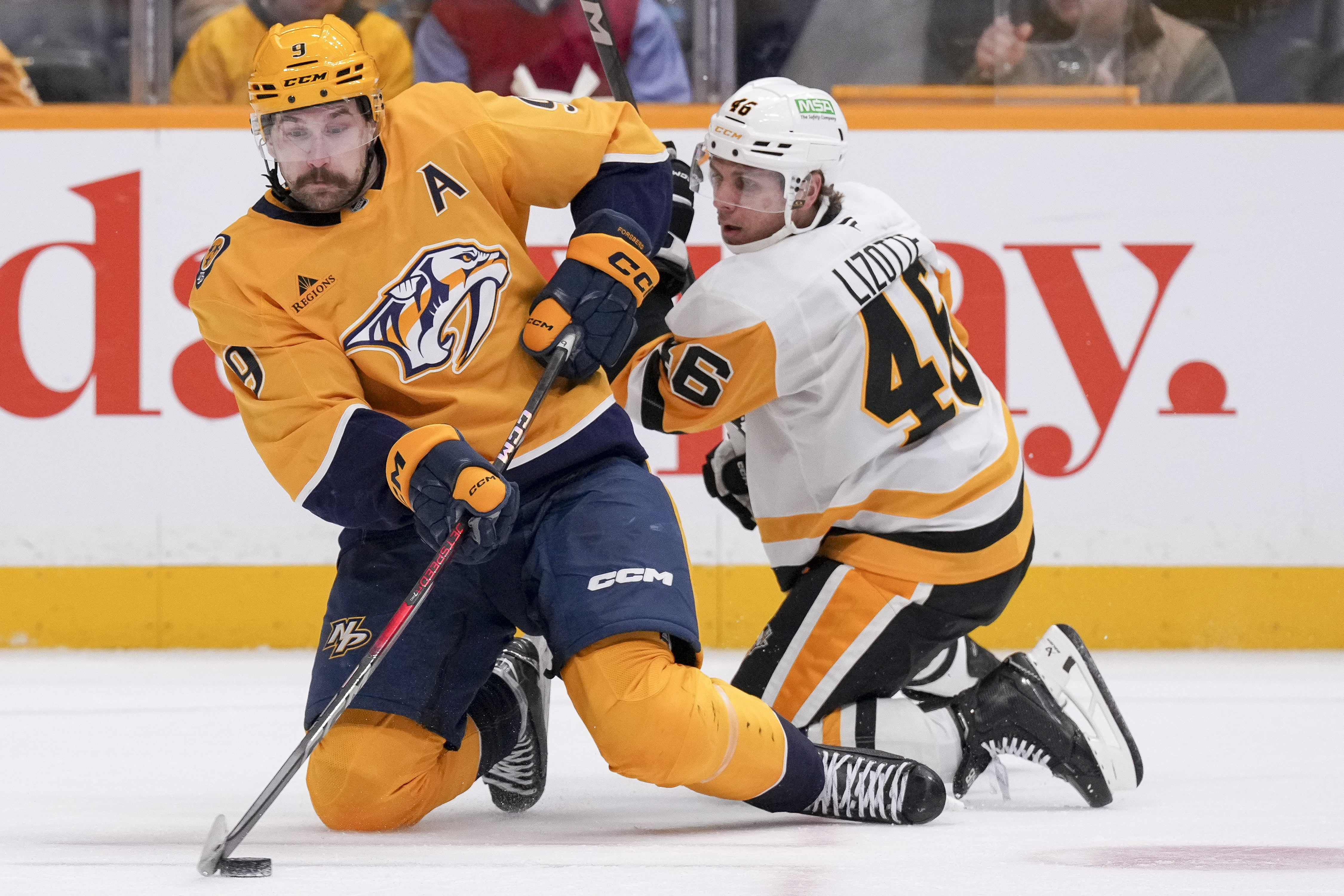 Nashville Predators left wing Filip Forsberg (9) passes the puck past Pittsburgh Penguins center Blake Lizotte (46) during the second period of an NHL hockey game Thursday, Dec. 19, 2024, in Nashville, Tenn.
