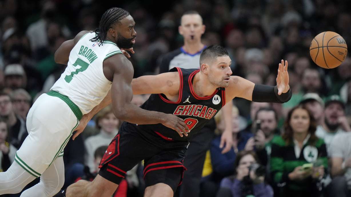 Boston Celtics guard Jaylen Brown (7) and Chicago Bulls center Nikola Vucevic (9) chase a loose ball in the second half of an NBA basketball game, Thursday, Dec. 19, 2024, in Boston.