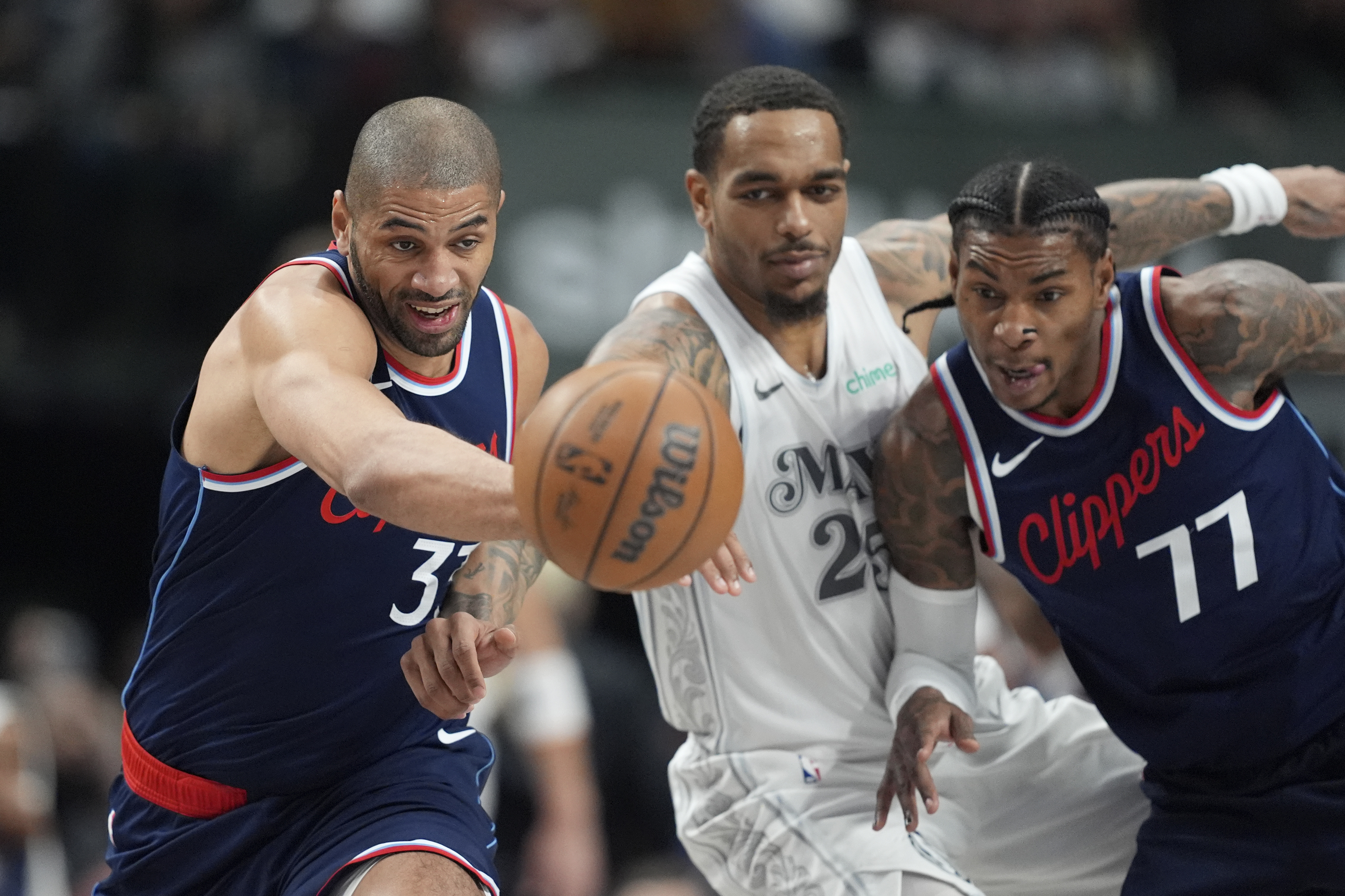 Los Angeles Clippers' Nicolas Batum (33), Dallas Mavericks' P.J. Washington, center, and Kevin Porter Jr. (77) sprint after a loose ball in the first half of an NBA basketball game in Dallas, Thursday, Dec. 19, 2024.