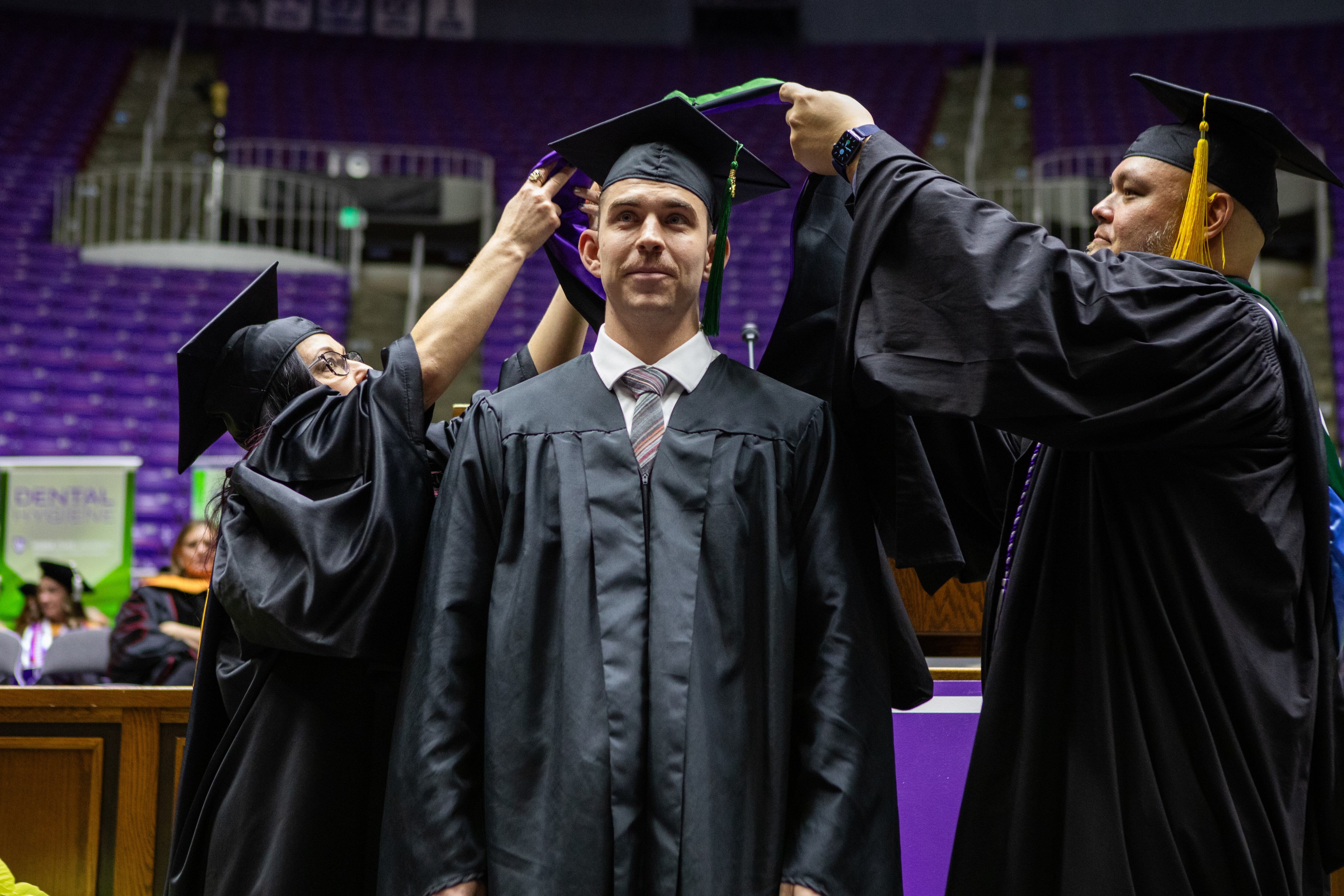 Weber State physician assistant master's degree graduate Collin Stoker, center, is honored by faculty members during the Ogden school's graduation exercises on Dec. 13.