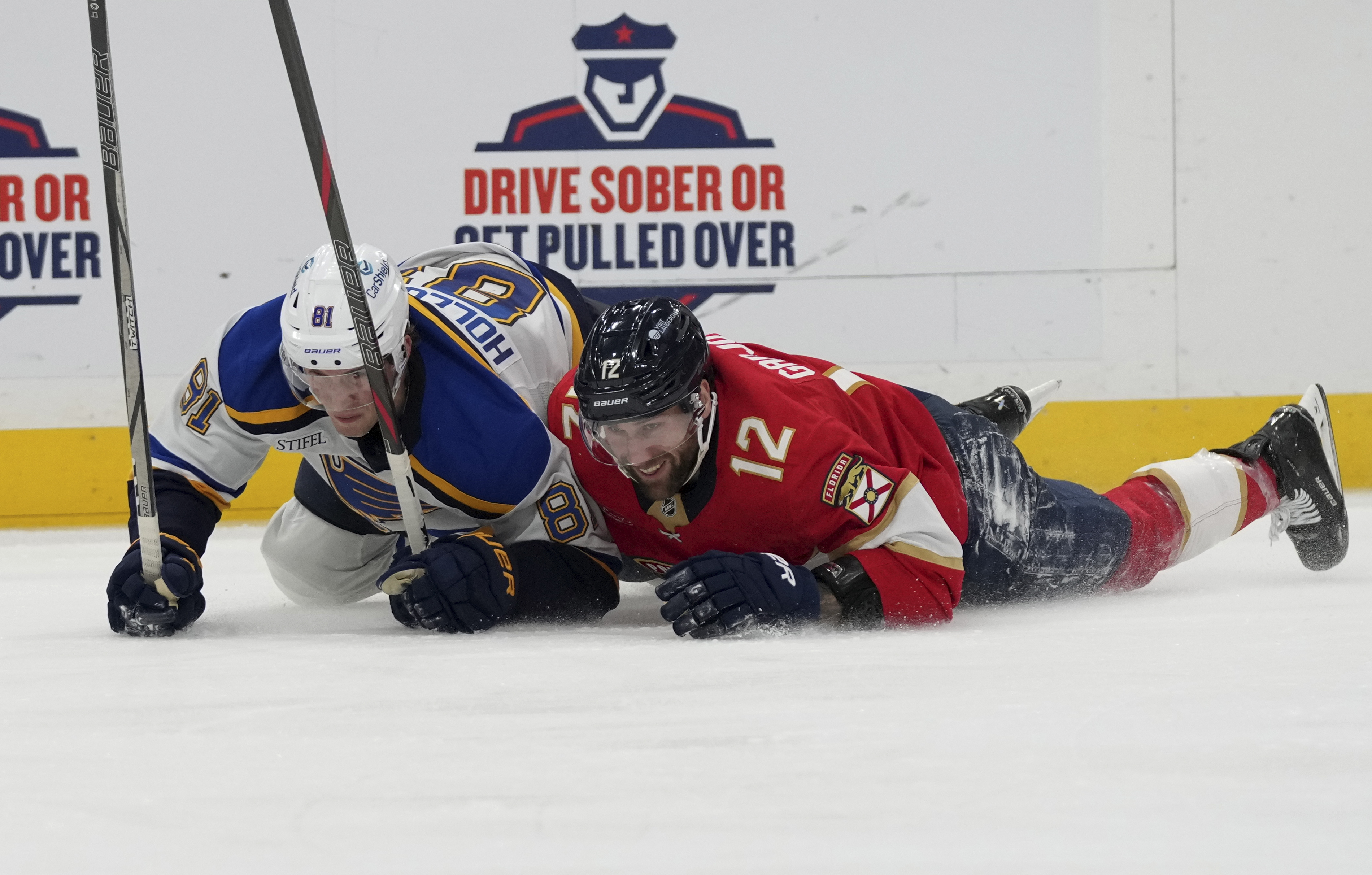 St. Louis Blues center Dylan Holloway (81) and Florida Panthers left wing Jonah Gadjovich (12) fall to the ice during the second period of an NHL hockey game, Friday, Dec. 20, 2024, in Sunrise, Fla.
