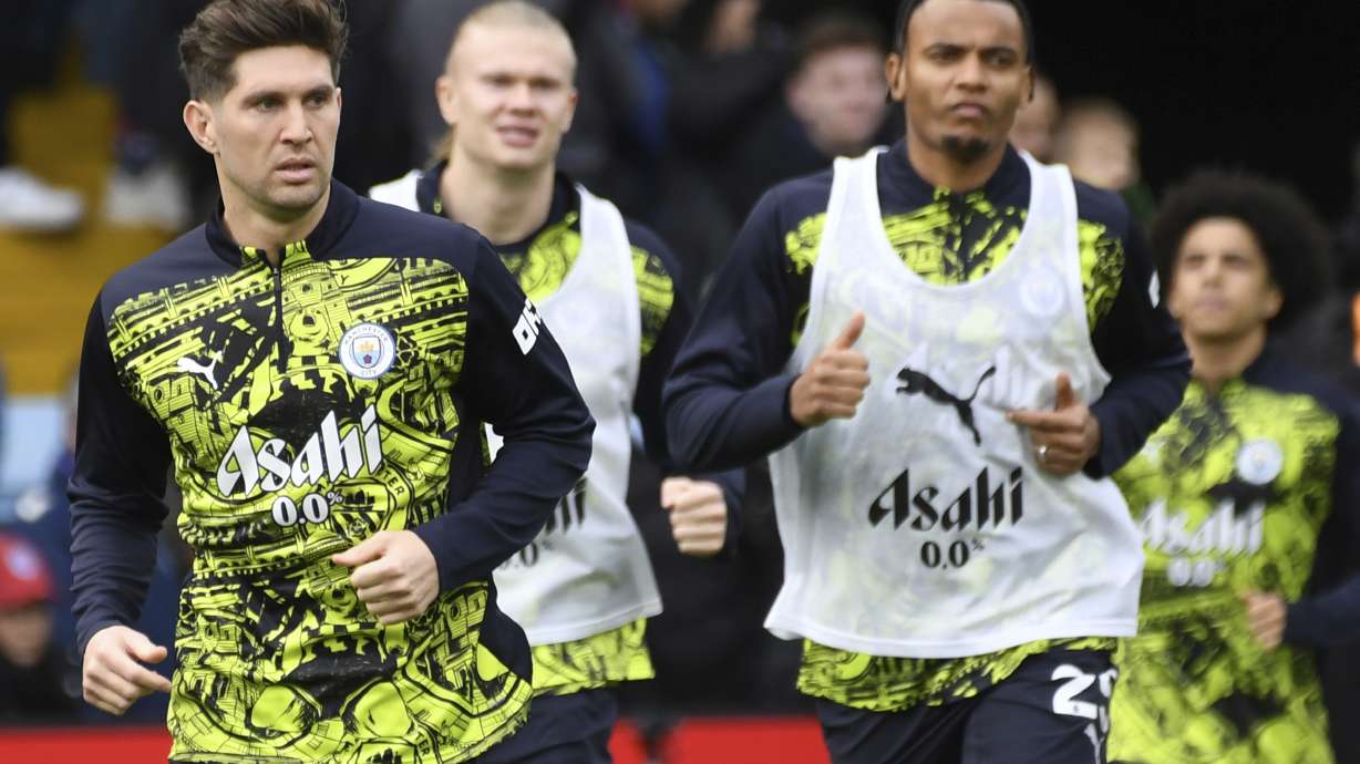 Manchester City's John Stones, left, runs during the warm up before the English Premier League soccer match between Aston Villa and Manchester City, at Villa Park in Birmingham, England, Saturday, Dec. 21, 2024.