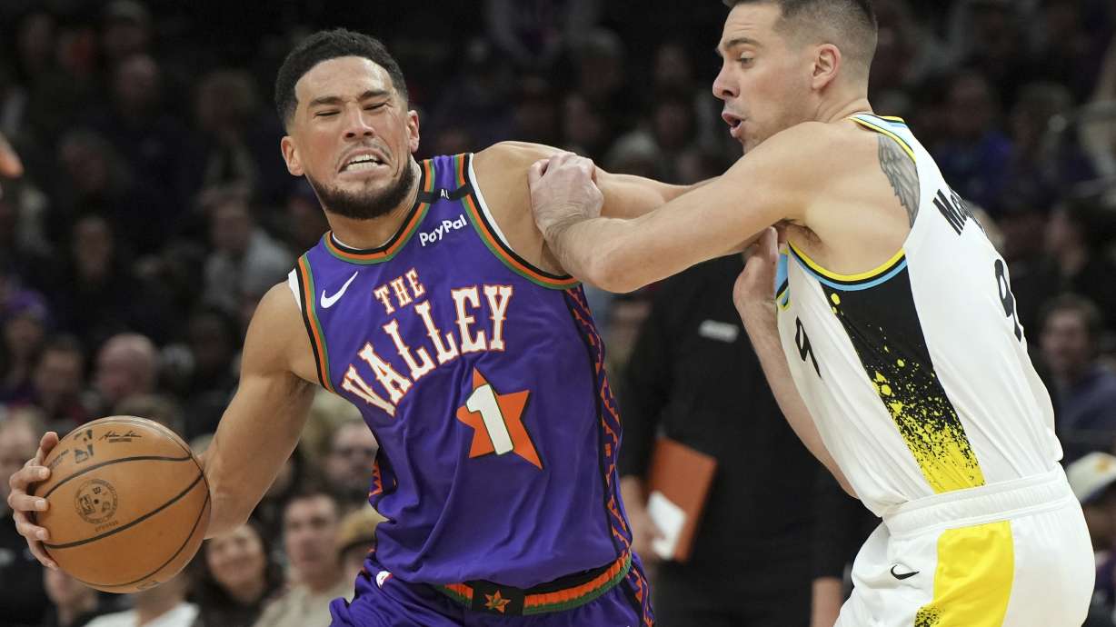 Phoenix Suns guard Devin Booker (1) drives on Indiana Pacers guard T.J. McConnell during the first half of an NBA basketball game, Thursday, Dec. 19, 2024, in Phoenix.