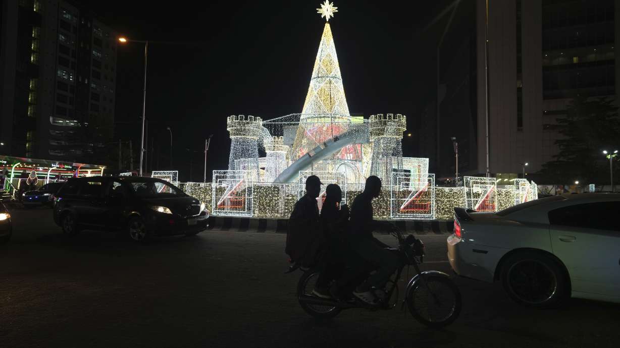 A man rides a motorcycle taxi past Christmas decorations on a street in Lagos, Nigeria, Friday.