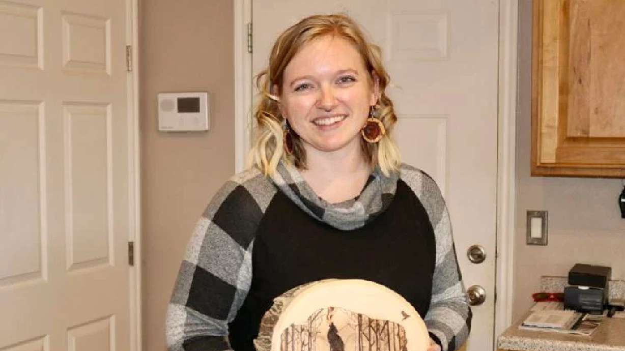 Artist Kira Johnson poses with one of her hand-burned wood art pieces in St. George on Nov. 12.