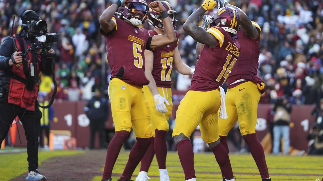 Washington Commanders wide receiver Olamide Zaccheaus (14) celebrating his touchdown with Washington Commanders quarterback Jayden Daniels (5) and others during the second half of an NFL football game against the Philadelphia Eagles, Sunday, Dec. 22, 2024, in Landover, Md.