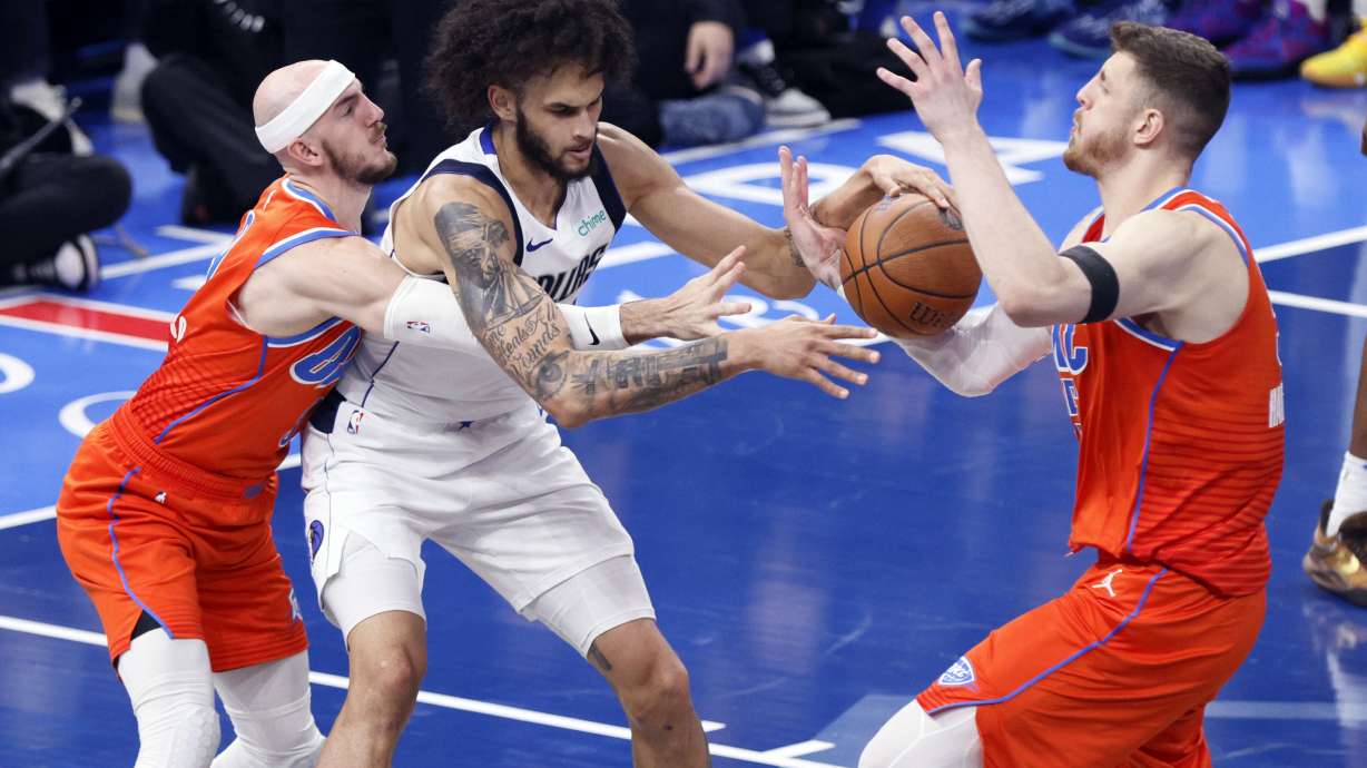 Oklahoma City Thunder center Isaiah Hartenstein, right, tries to steal the ball from Dallas Mavericks center Dereck Lively II, center, as Thunder guard Alex Caruso, left, defends during the first half of an Emirates NBA Cup basketball game, Tuesday, Dec. 10, 2024, in Oklahoma City.